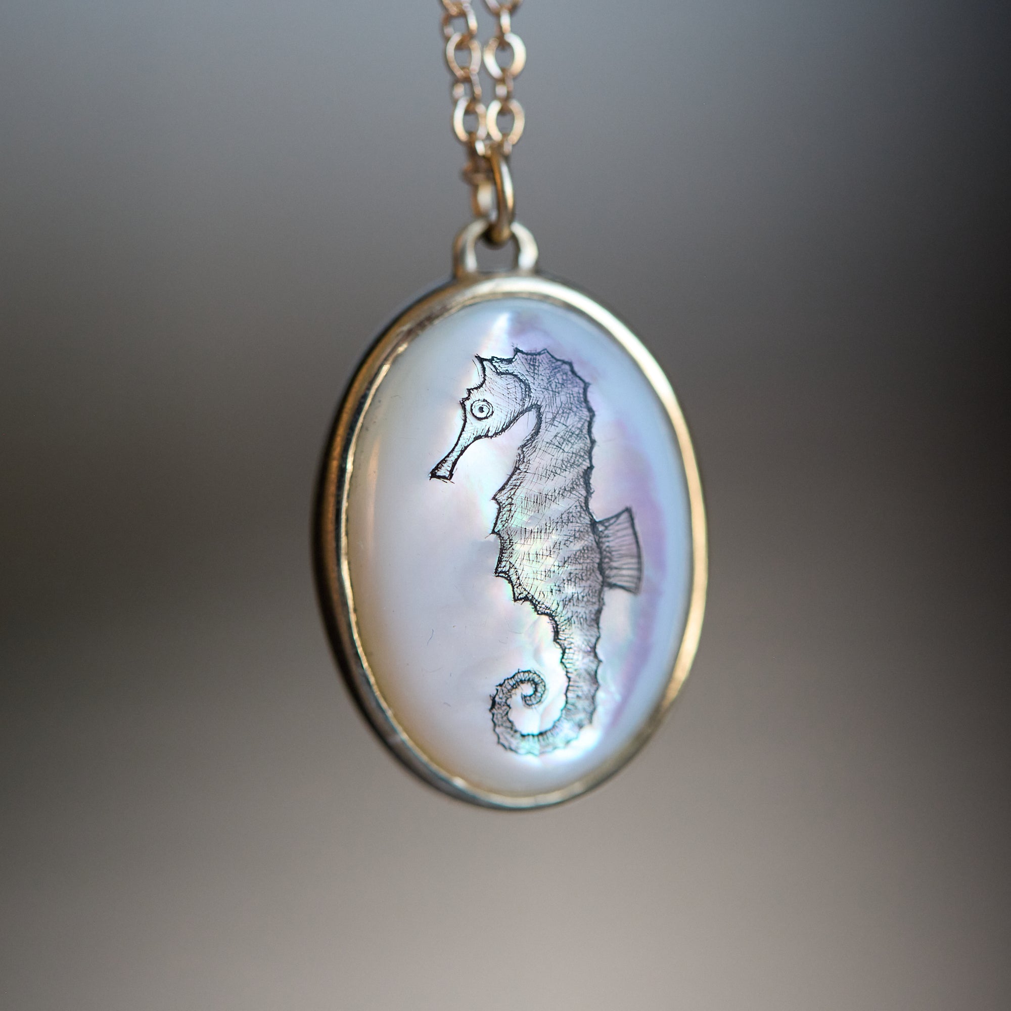 Seahorse pendant on a chain against a blurred background