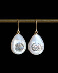Pair of teardrop-shaped earrings with shell designs on a black background