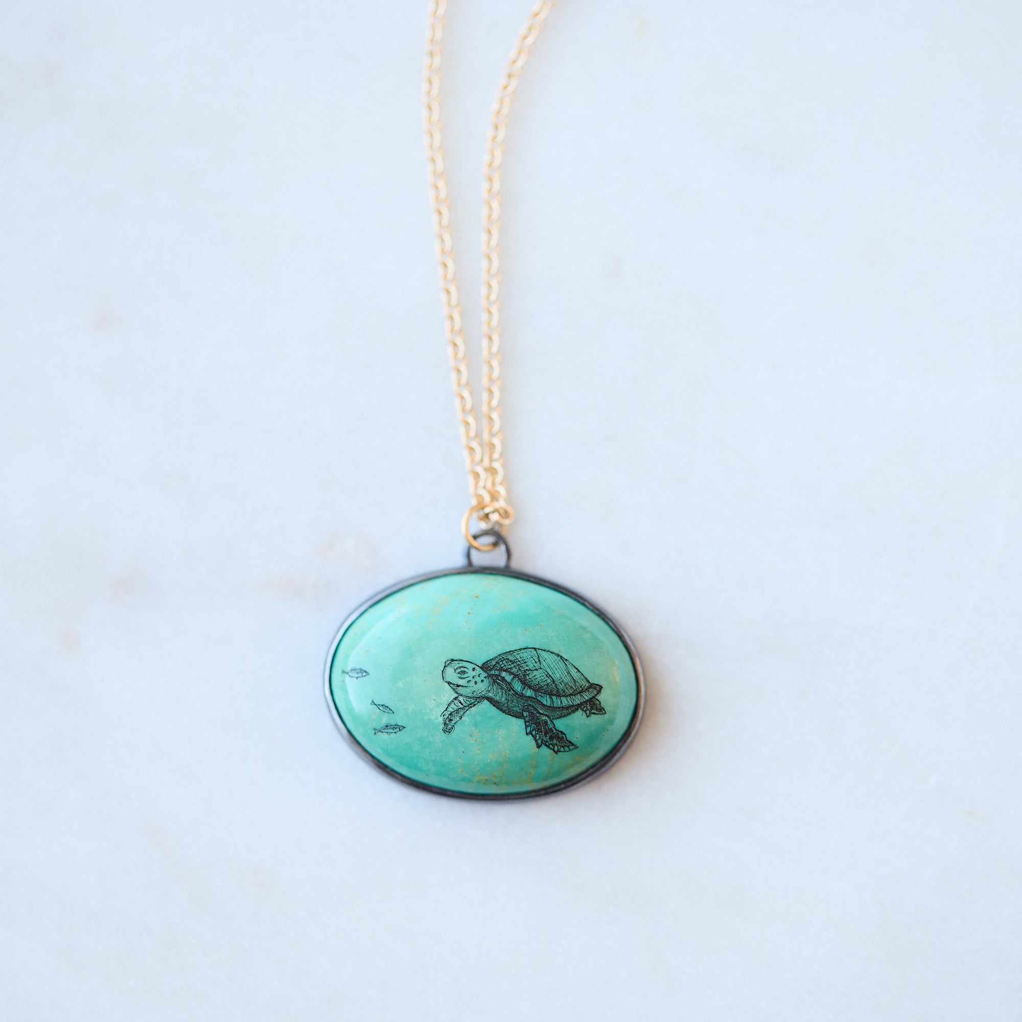Necklace with a round pendant featuring a turtle design on a light background