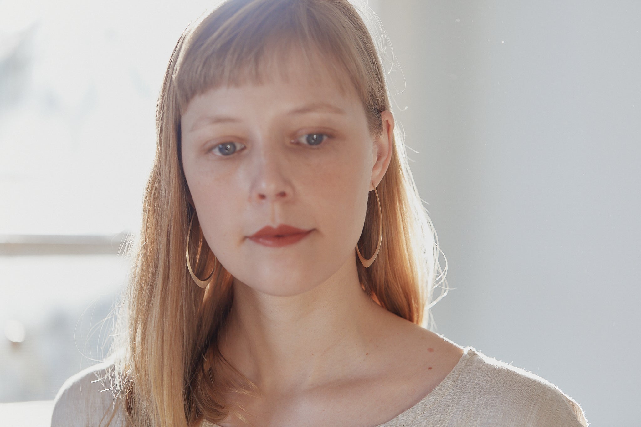 large gold facet hoops shown on person with red lipstick