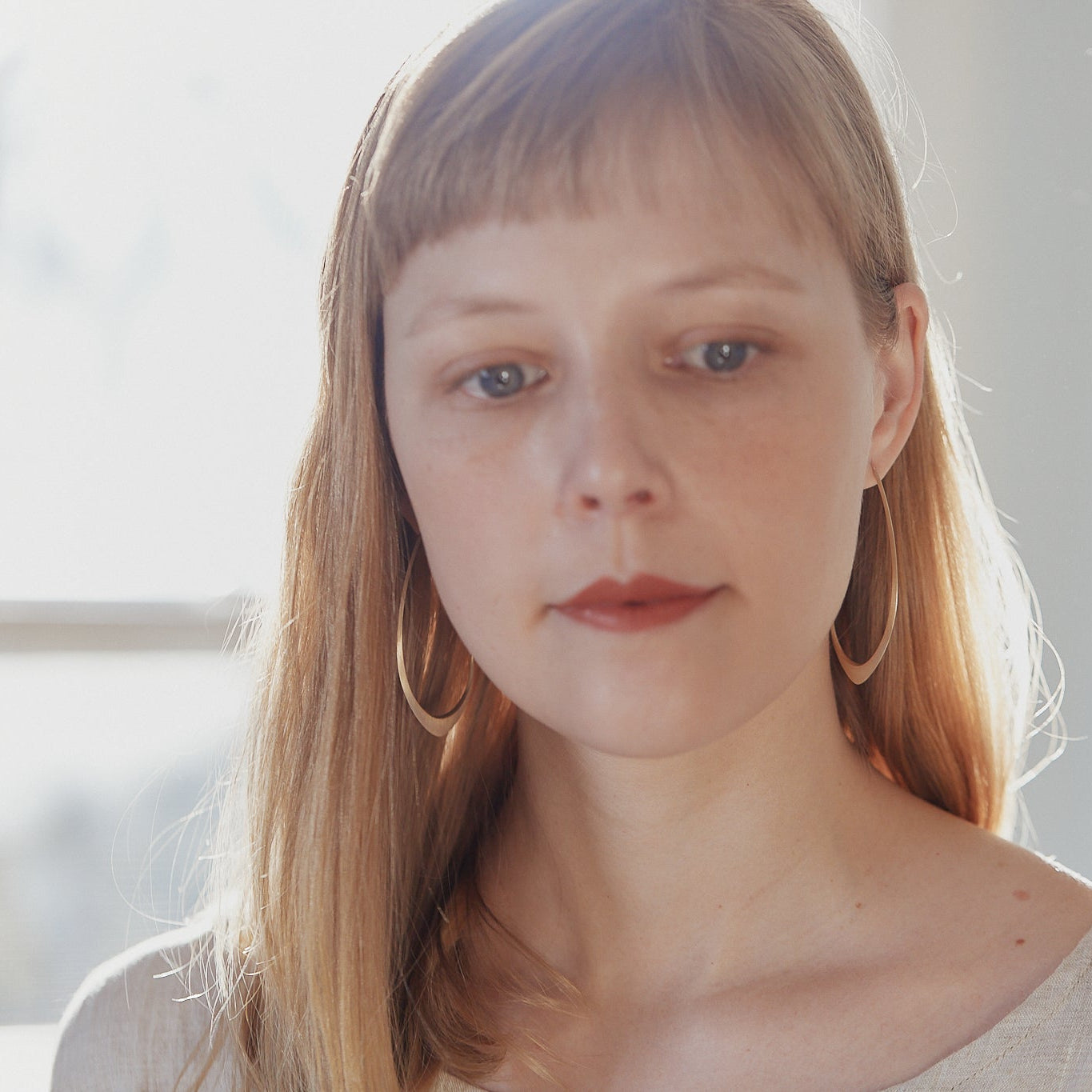 large gold facet hoops shown on person with red lipstick