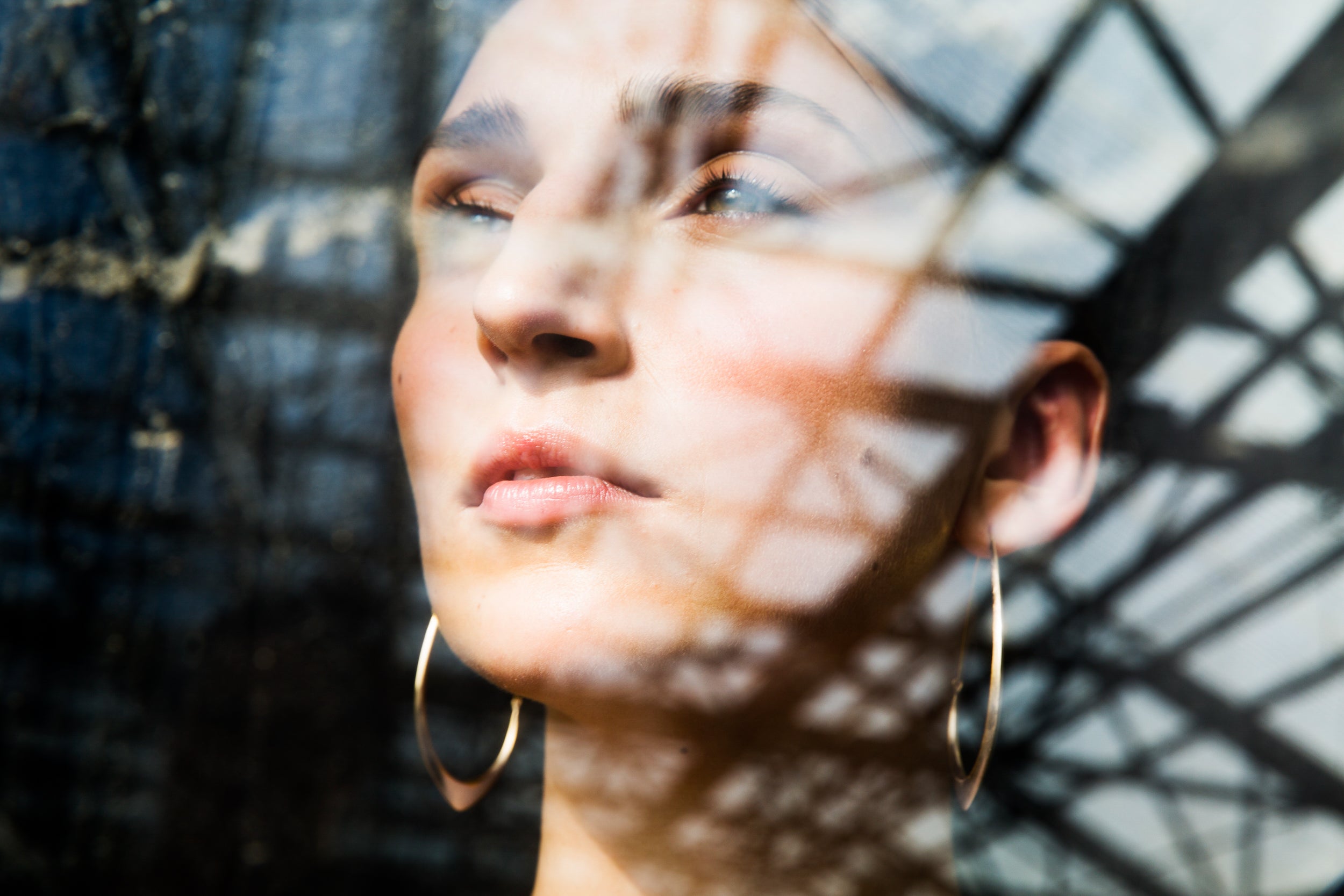large gold hoops shown on person, shown through a window with reflection