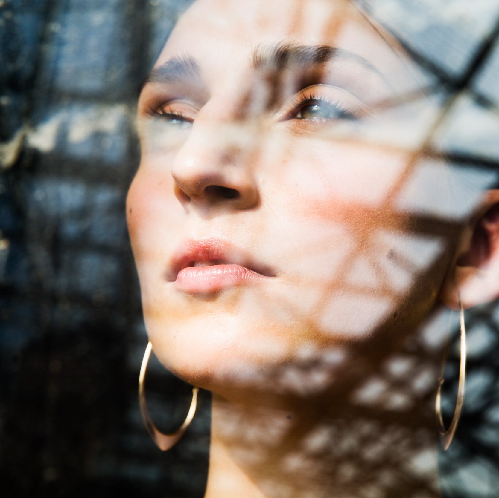 large gold hoops shown on person, shown through a window with reflection