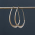 small gold facet hoops hanging from a bar against a grey background