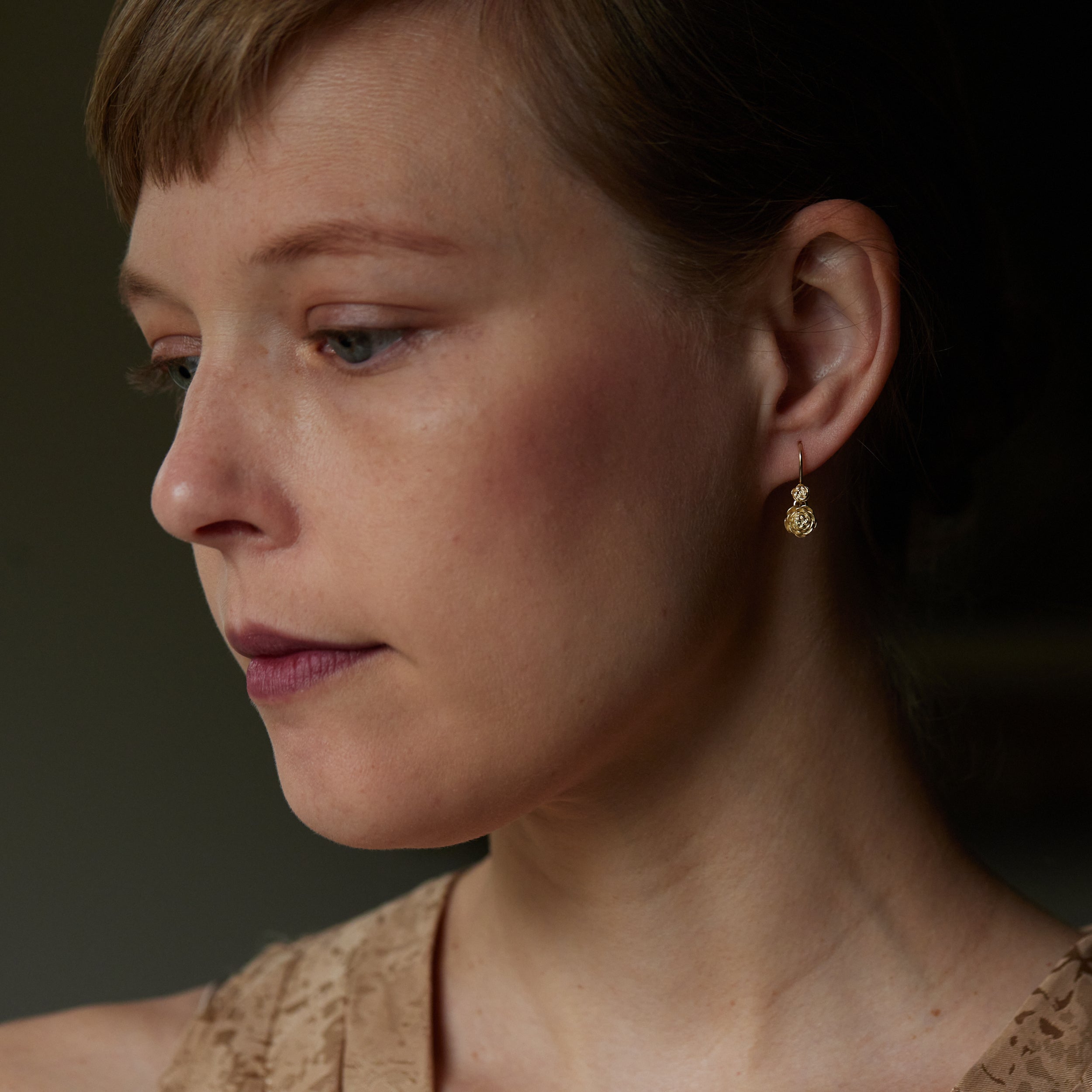 gold double rose earrings shown on person