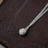 silver rose pendant necklace laying on leather book