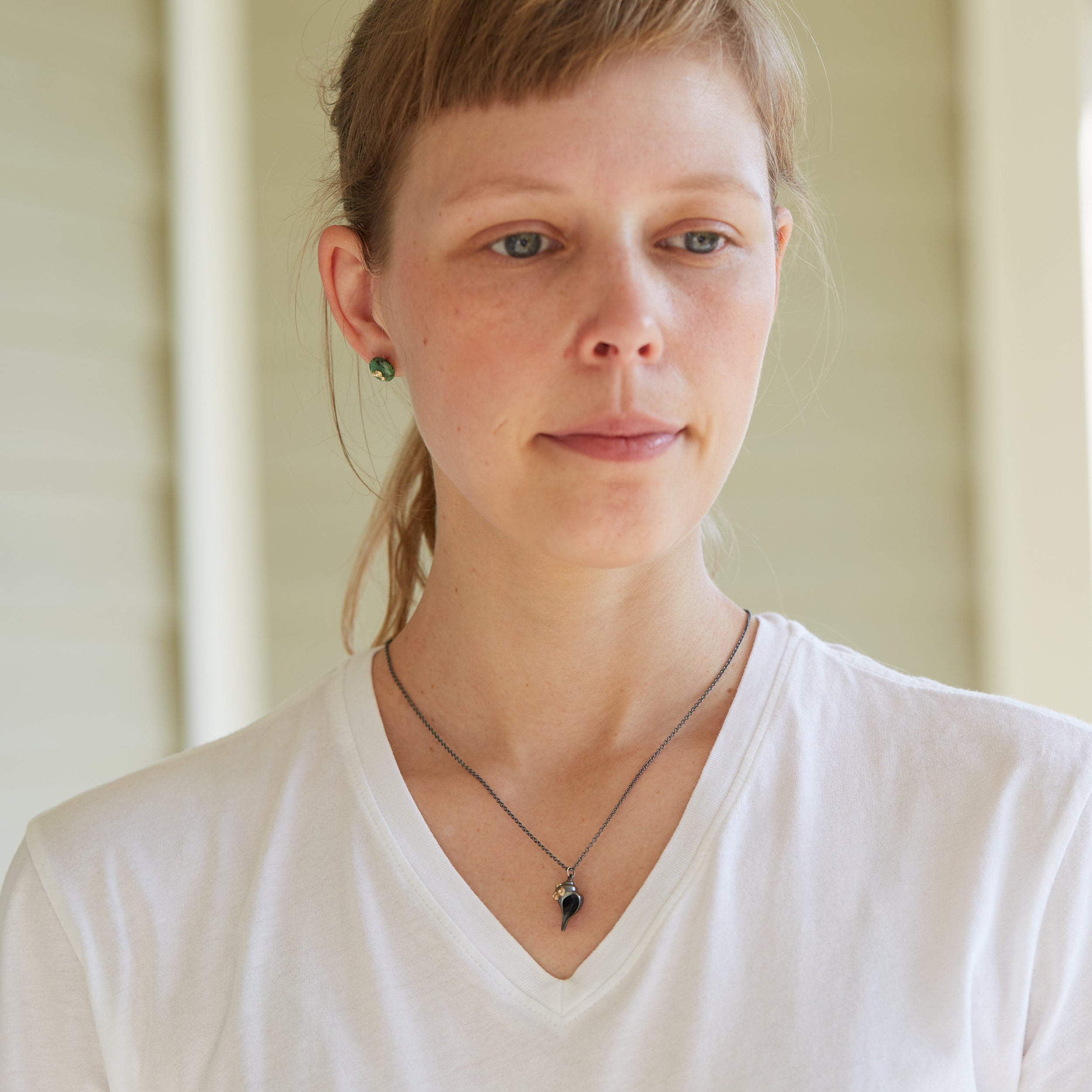 black whelk shell pendant with gold barnacles on chain on person