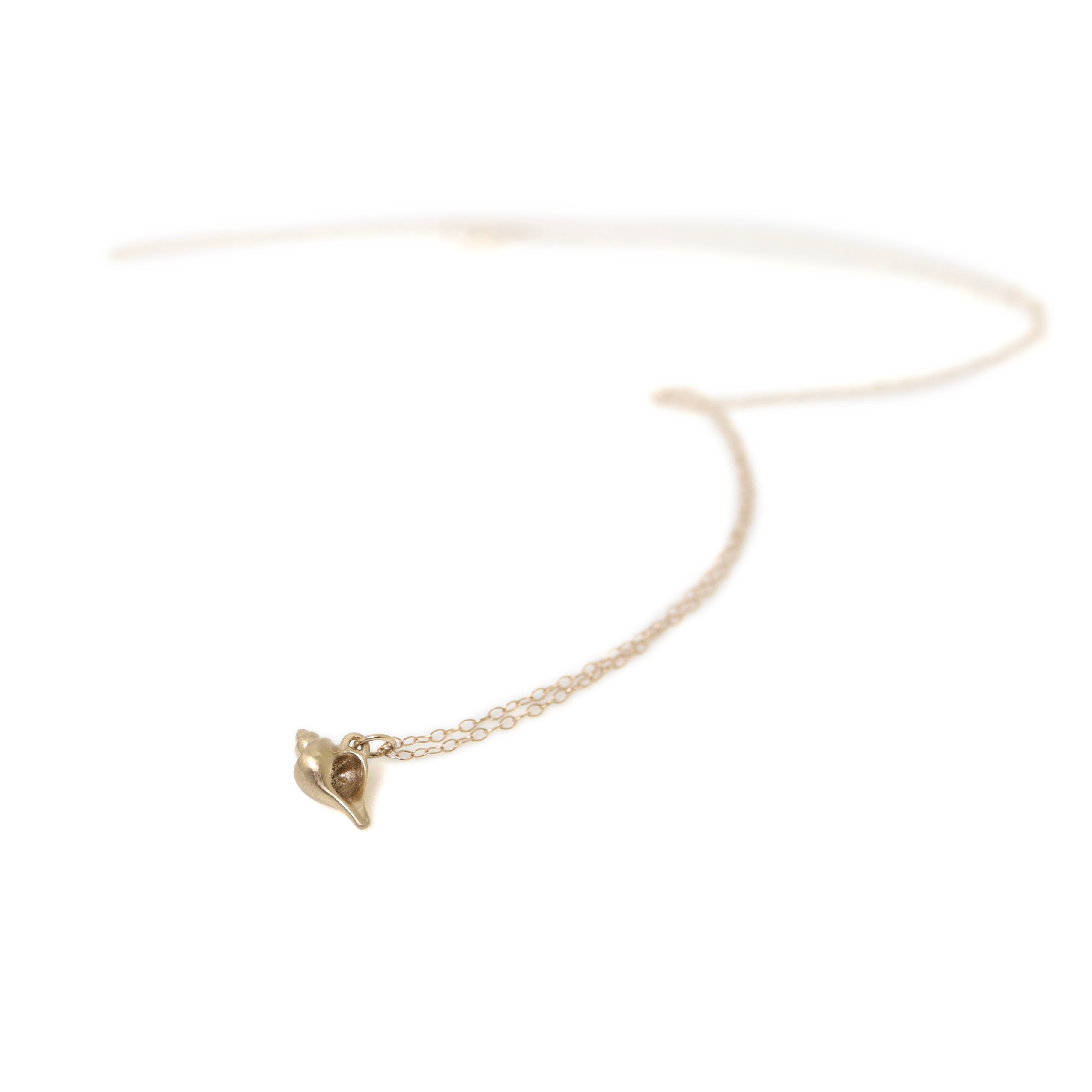 Tiny handcarved 14k gold whelk shell by Hannah Blount