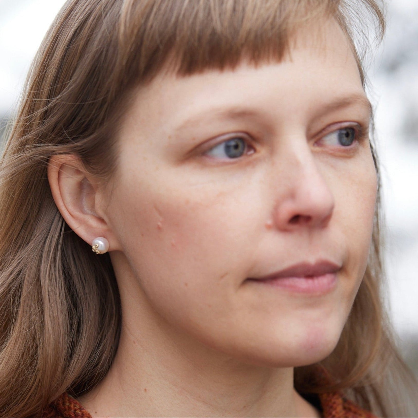 Medium pearl studs with gold barnacles, photographed on person.