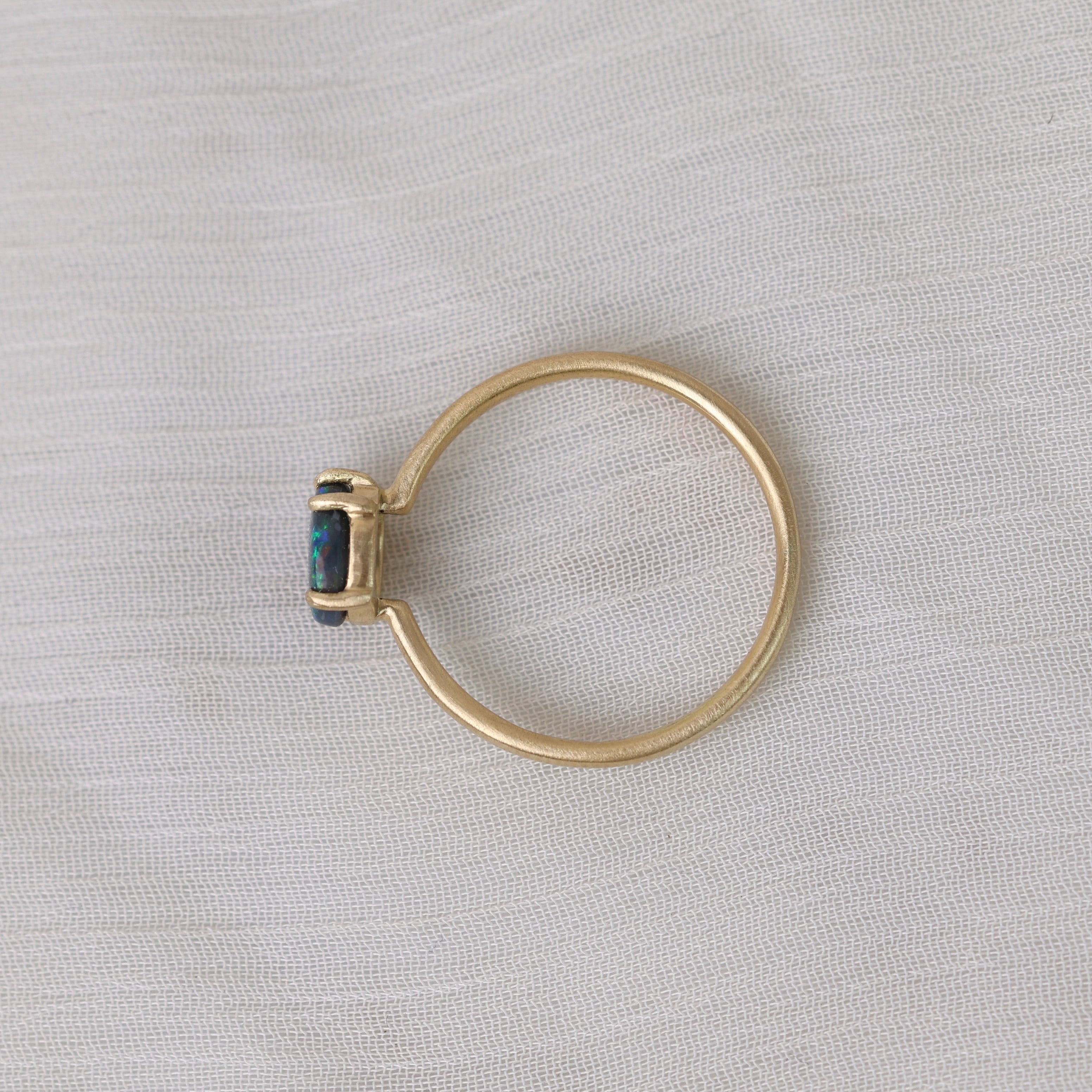 colorful opal in delicate gold prongs on a white background