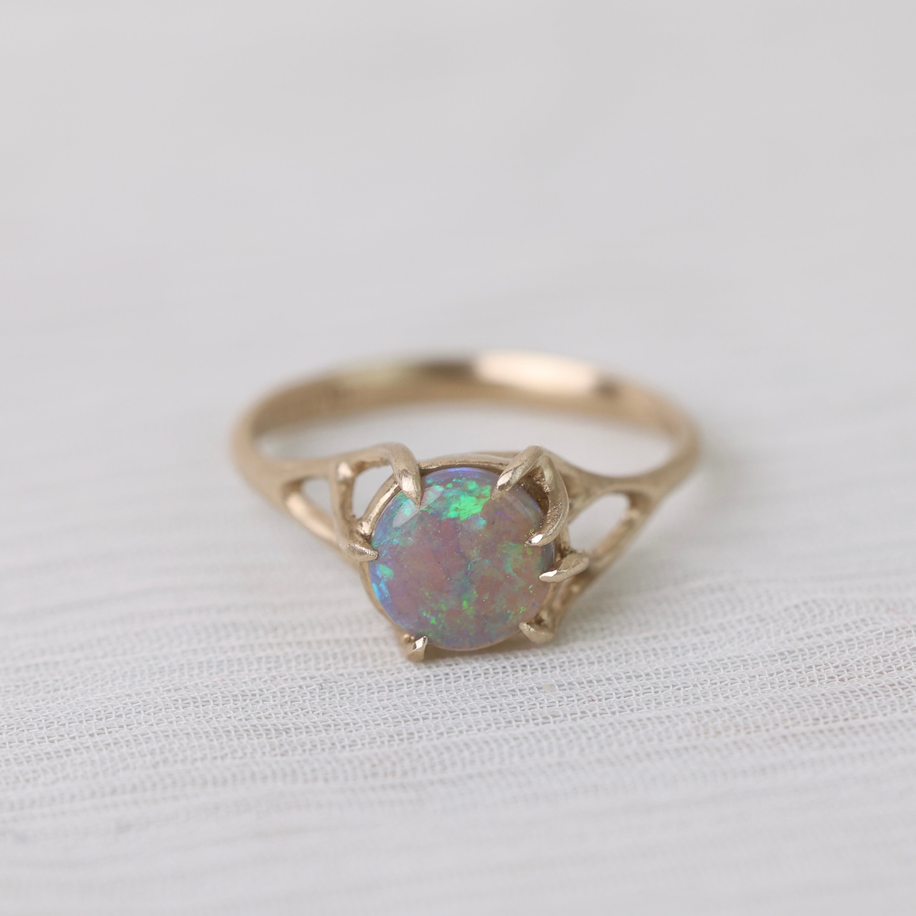 Colorful opal in delicate gold prongs on a white background