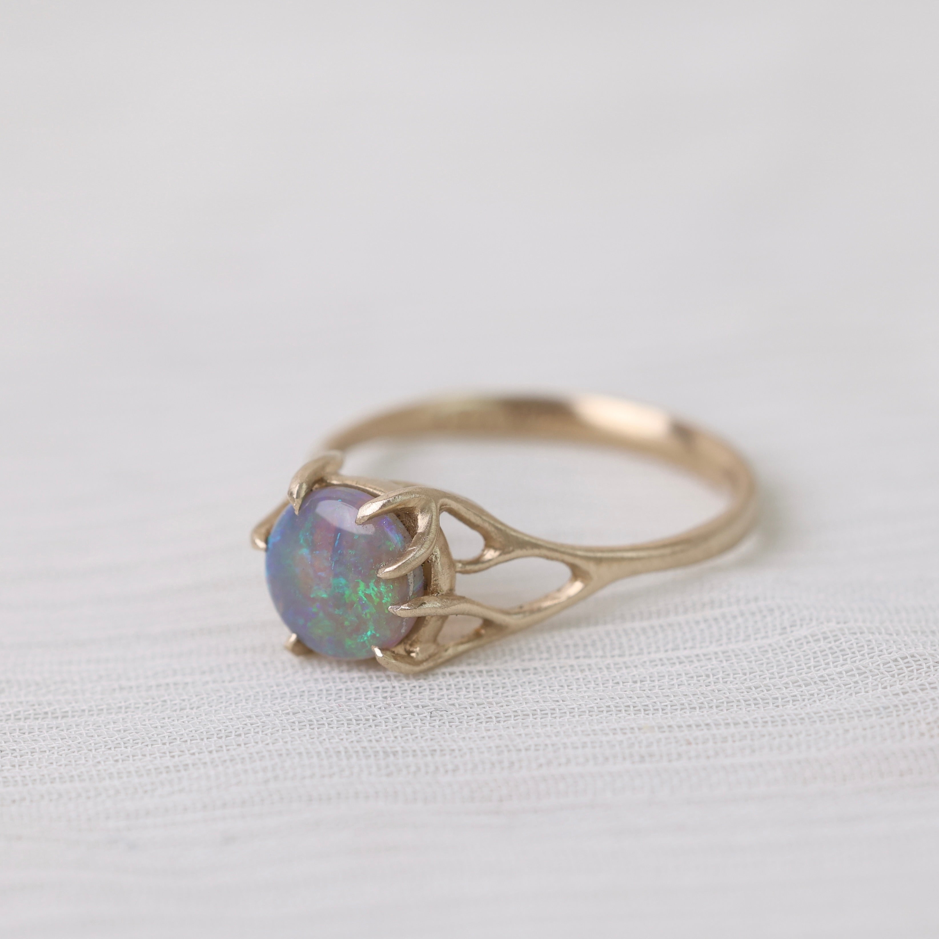 Colorful opal in delicate gold prongs on a white background