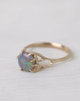 Colorful opal in delicate gold prongs on a white background