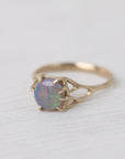 Colorful opal in delicate gold prongs on a white background