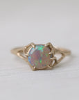 Colorful opal in delicate gold prongs on a white background