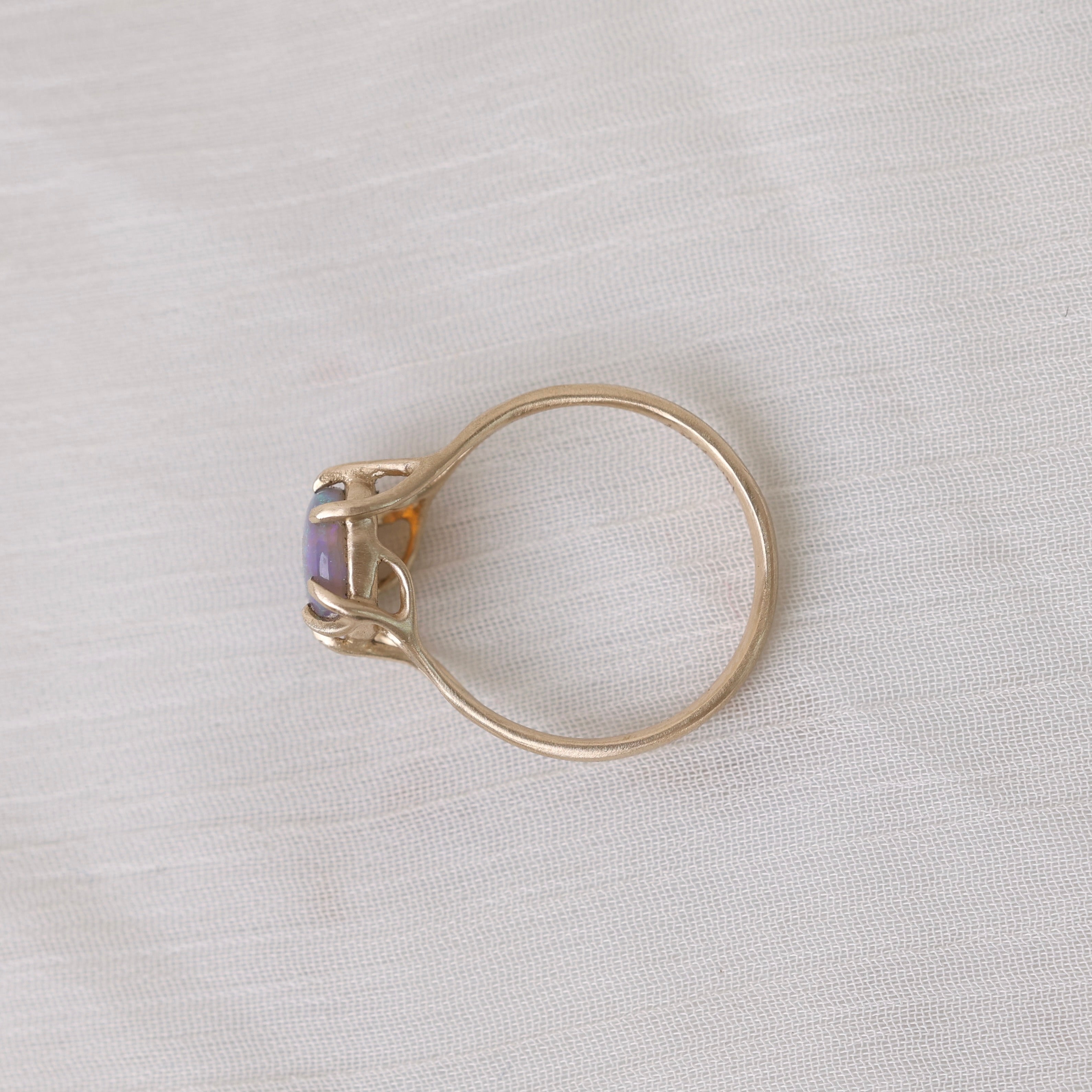 Colorful opal in delicate gold prongs on a white background