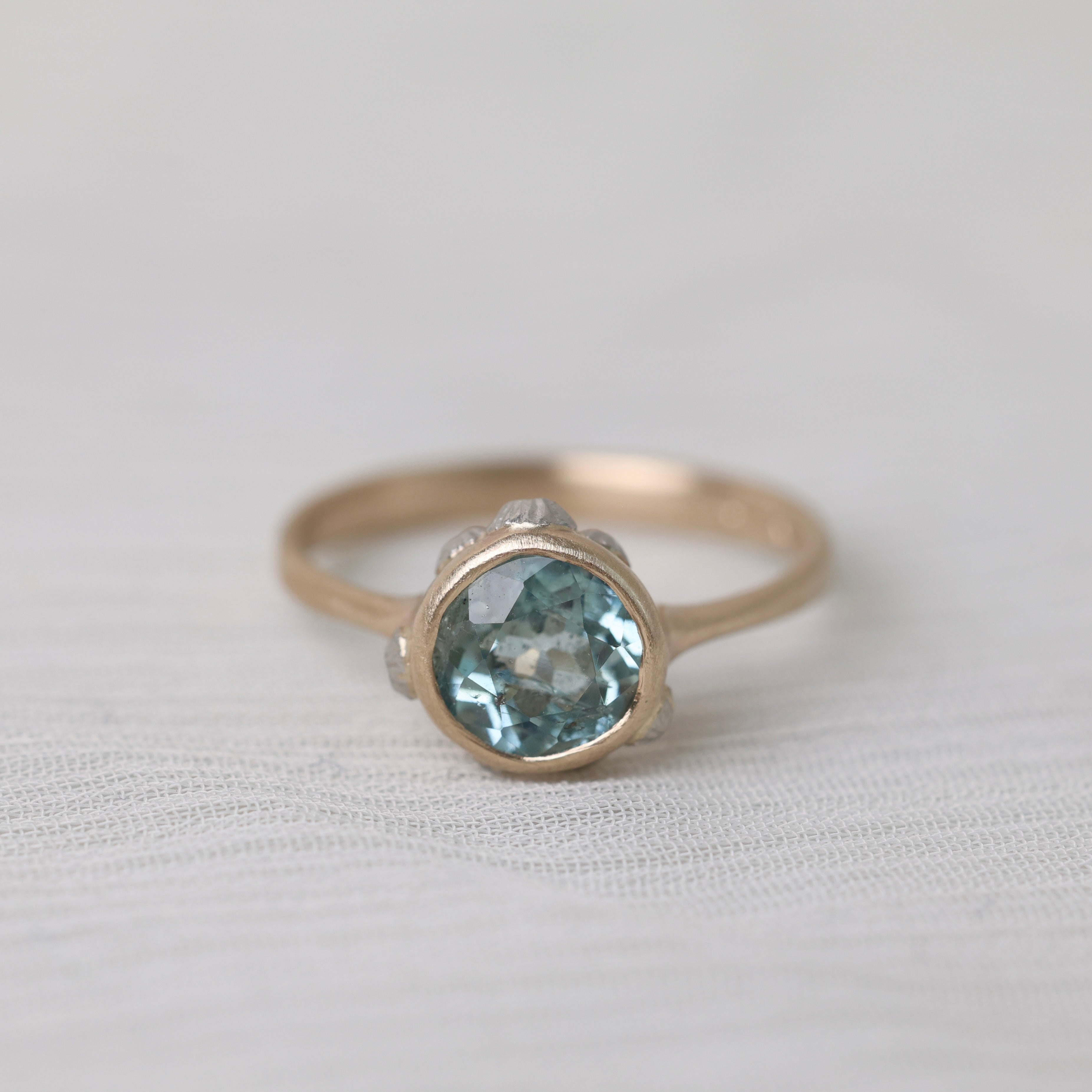 gold ring with light blue stone on white background