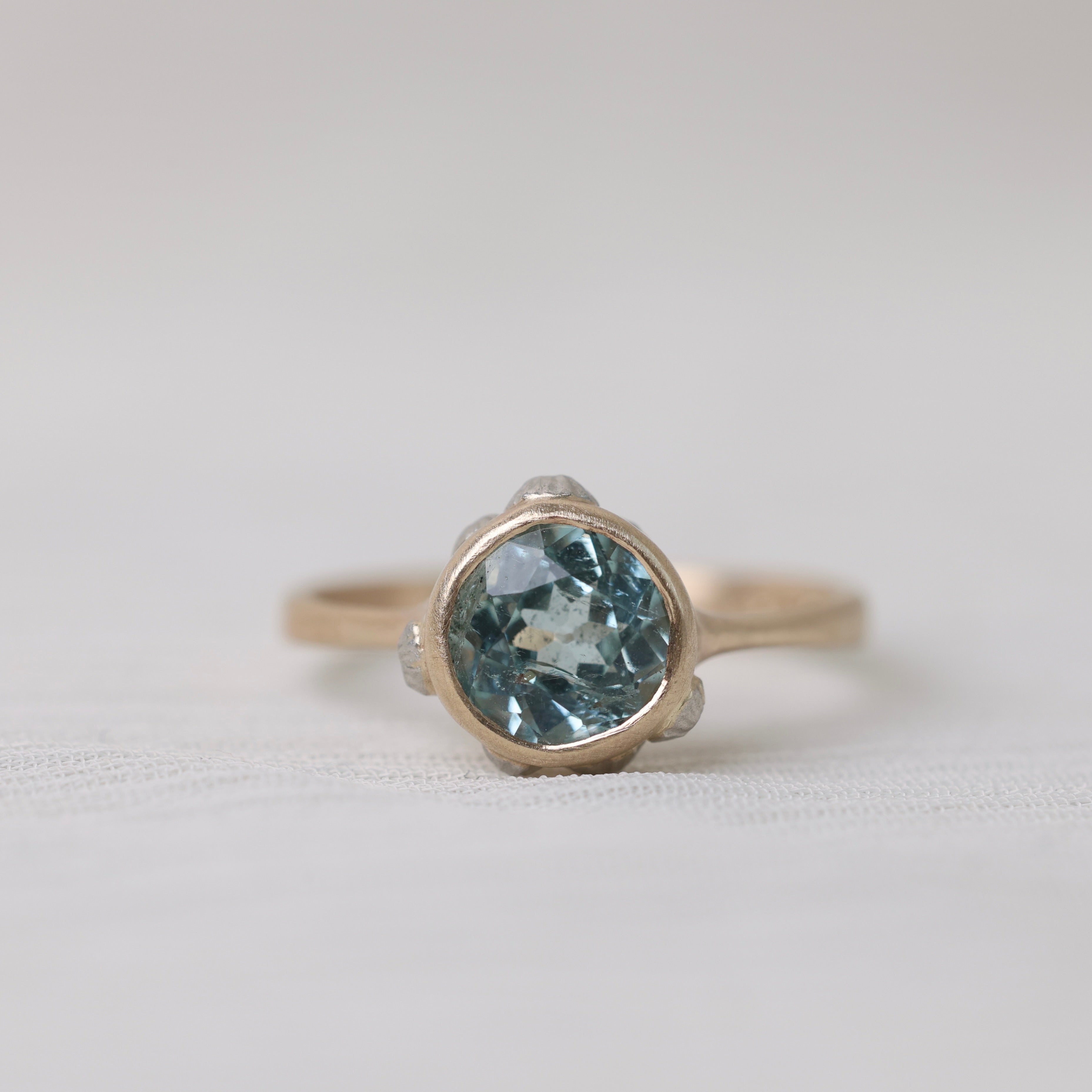 gold ring with light blue stone on white background