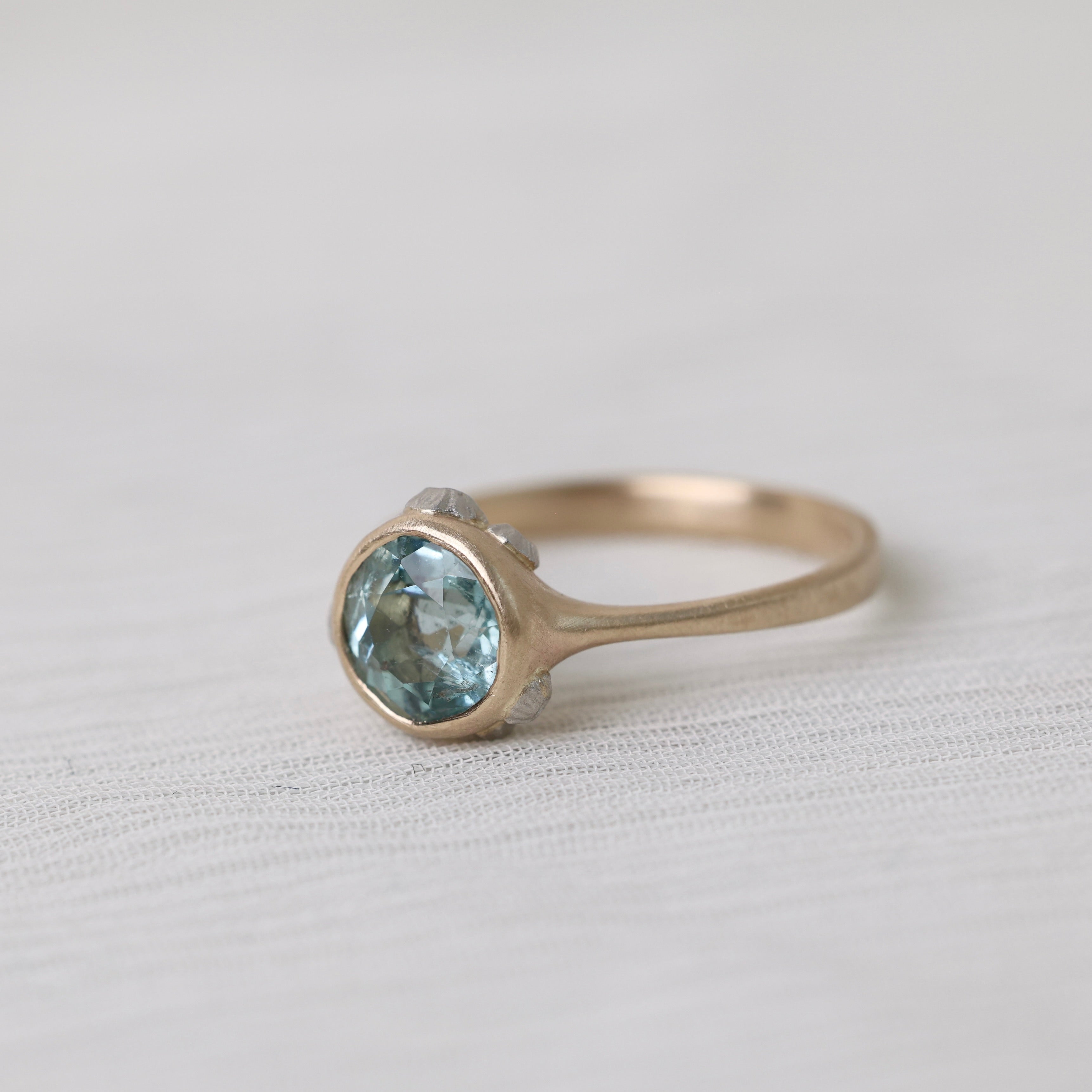 gold ring with light blue stone on white background