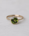 Gold ring with bright green stone and silver barnacles on white background
