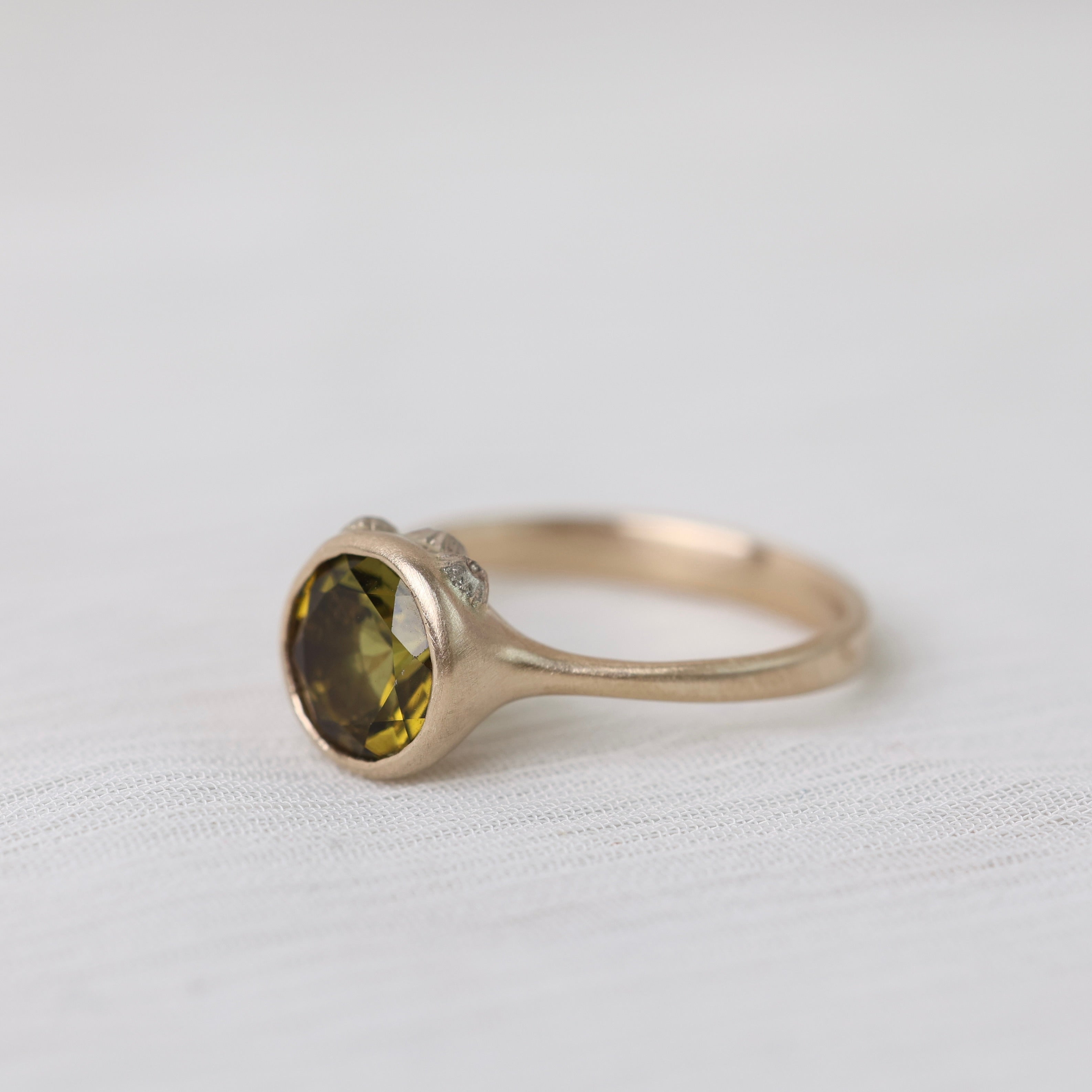 Olive green stone gold ring on white background with barnacles 