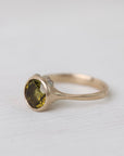 Olive green stone gold ring on white background with barnacles 
