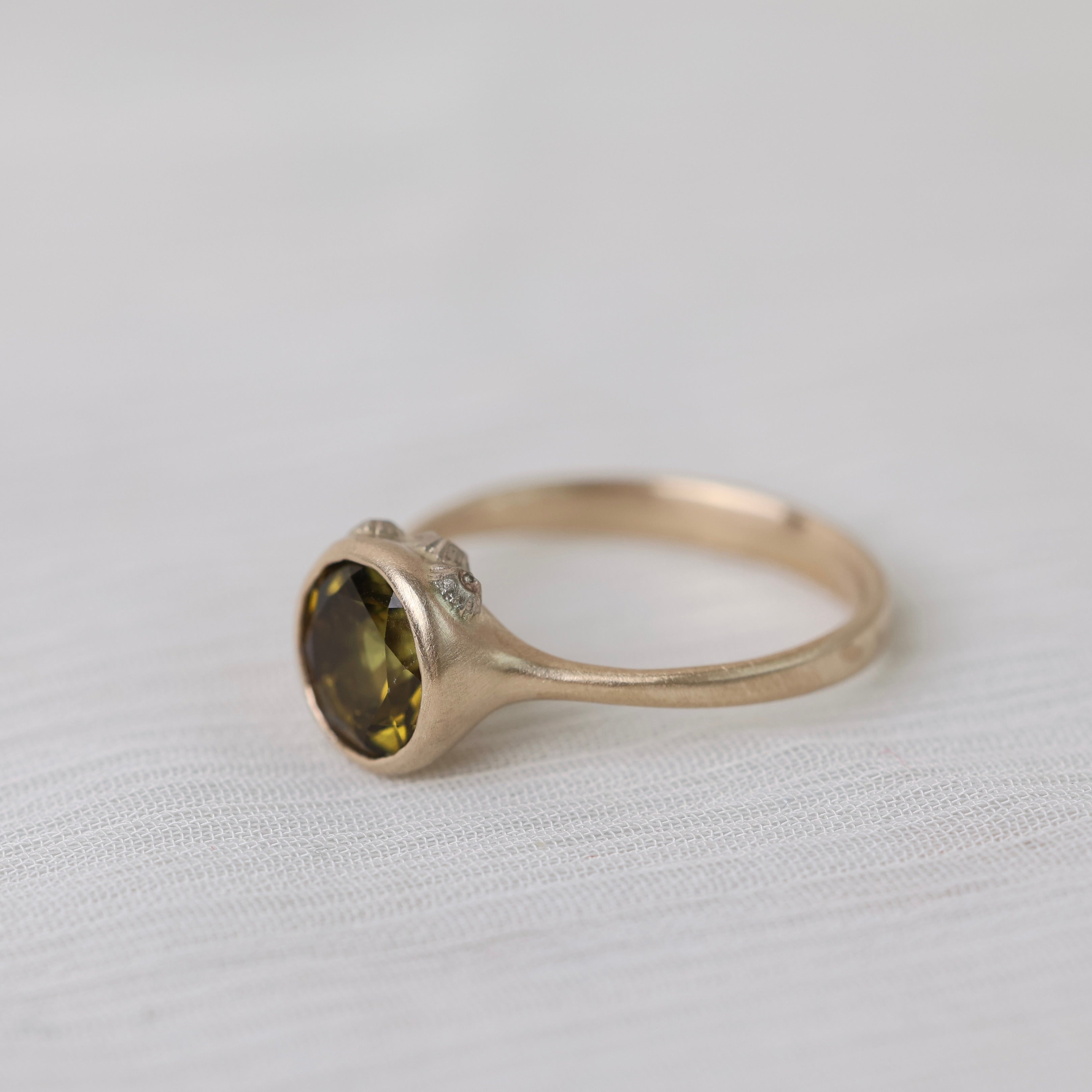 Olive green stone gold ring on white background with barnacles