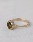 Olive green stone gold ring on white background with barnacles