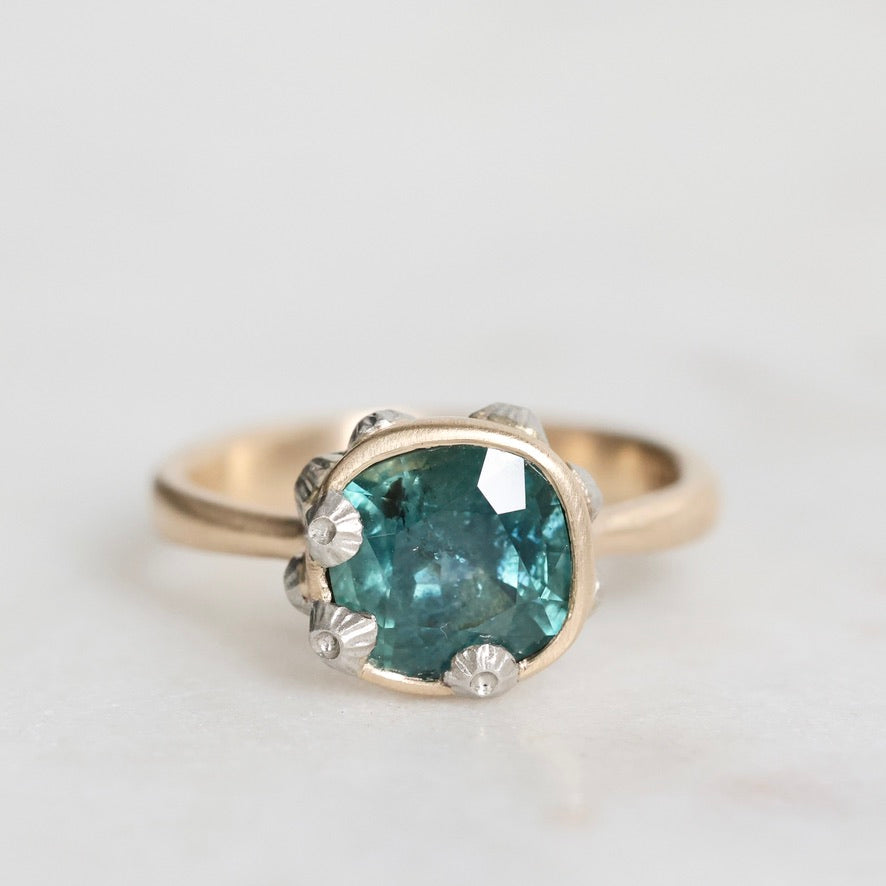 Ring with a blue gemstone and silver accents on a light gray background