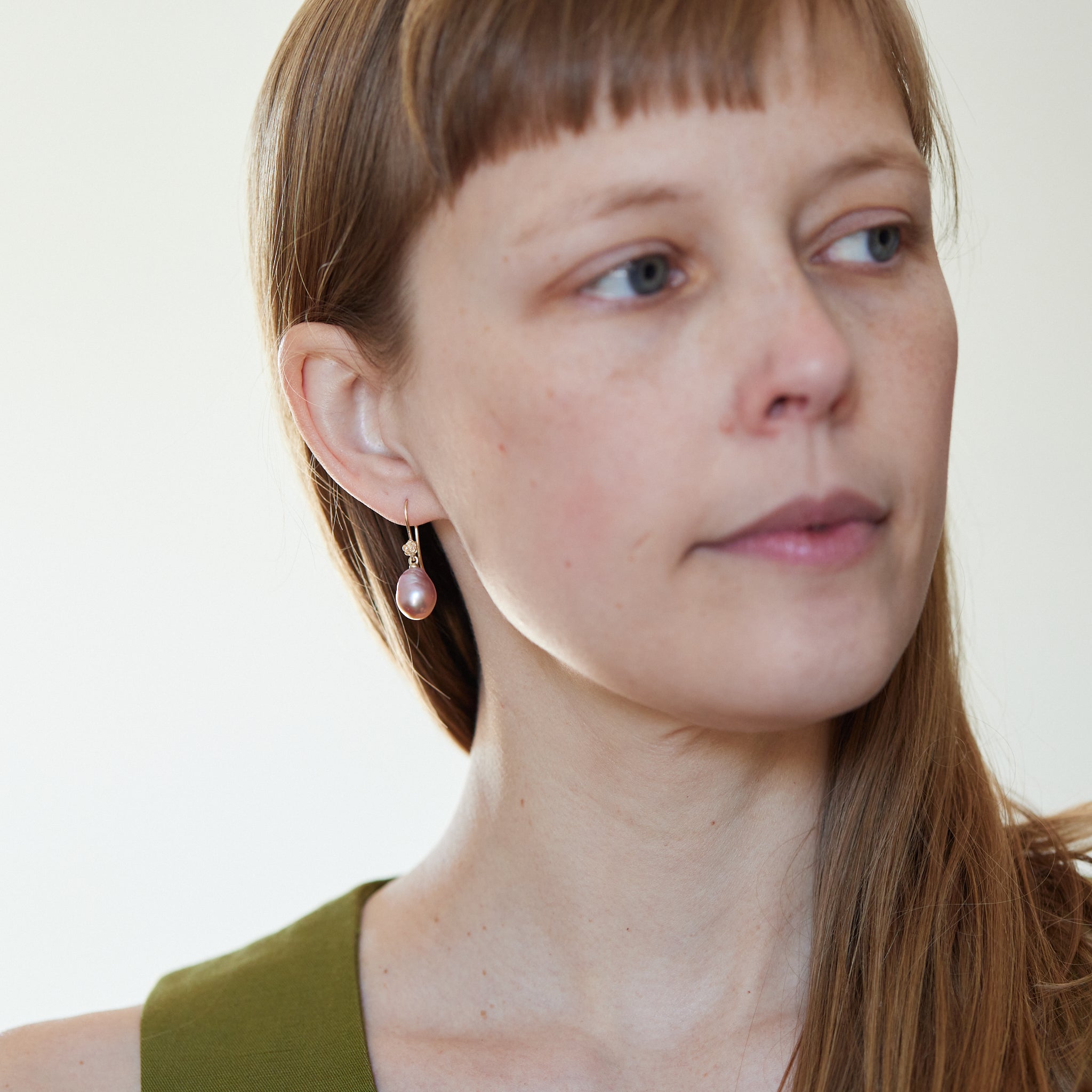 On Person: A pink pearl drop earring with 14k yellow gold ear wires and rose accent. 