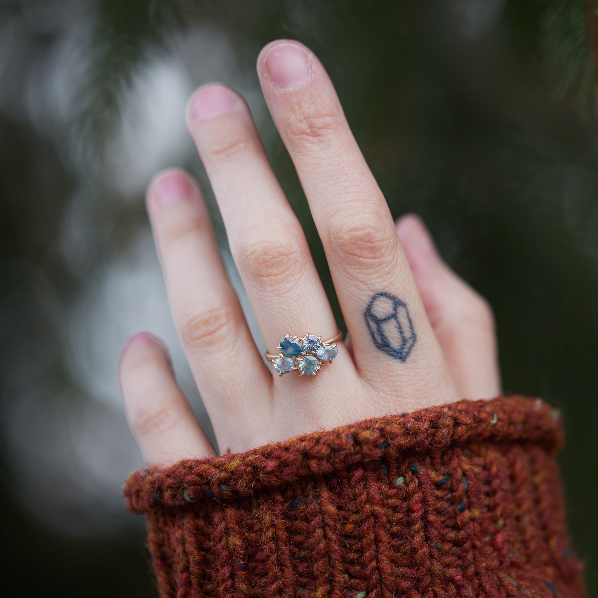 five montana sapphires of various shapes are set in a cluster with gold prongs in a gold ring