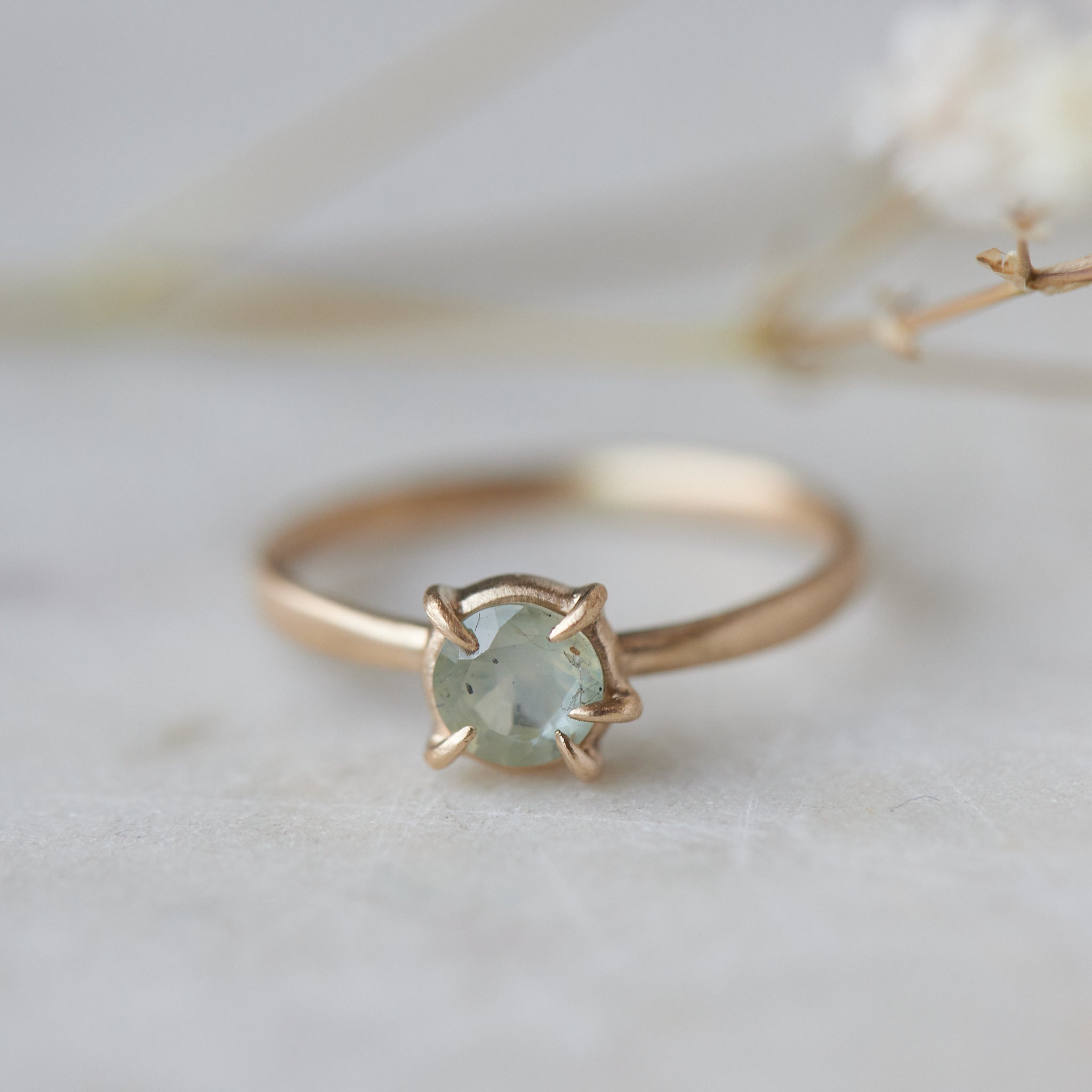 side view of round cream montana sapphire set in a ring of prongs in a gold ring