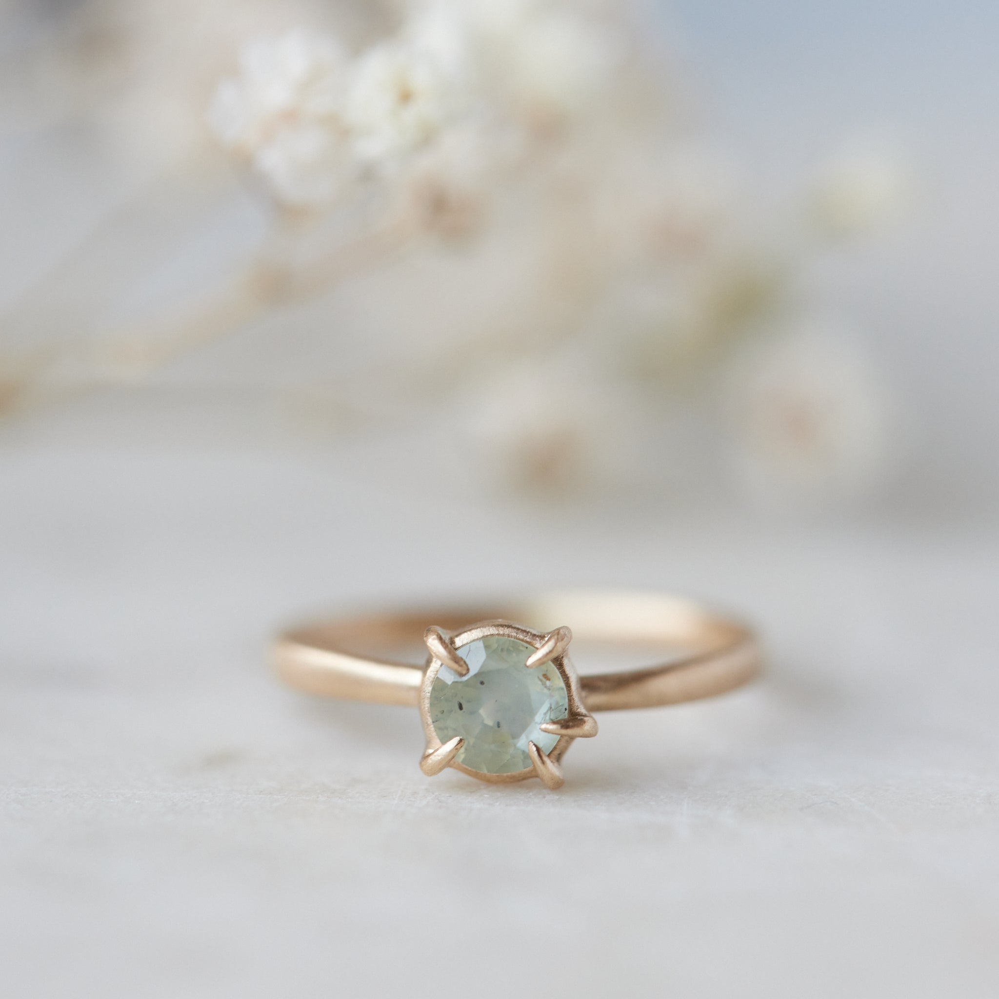 side view of round cream montana sapphire set in a ring of prongs in a gold ring