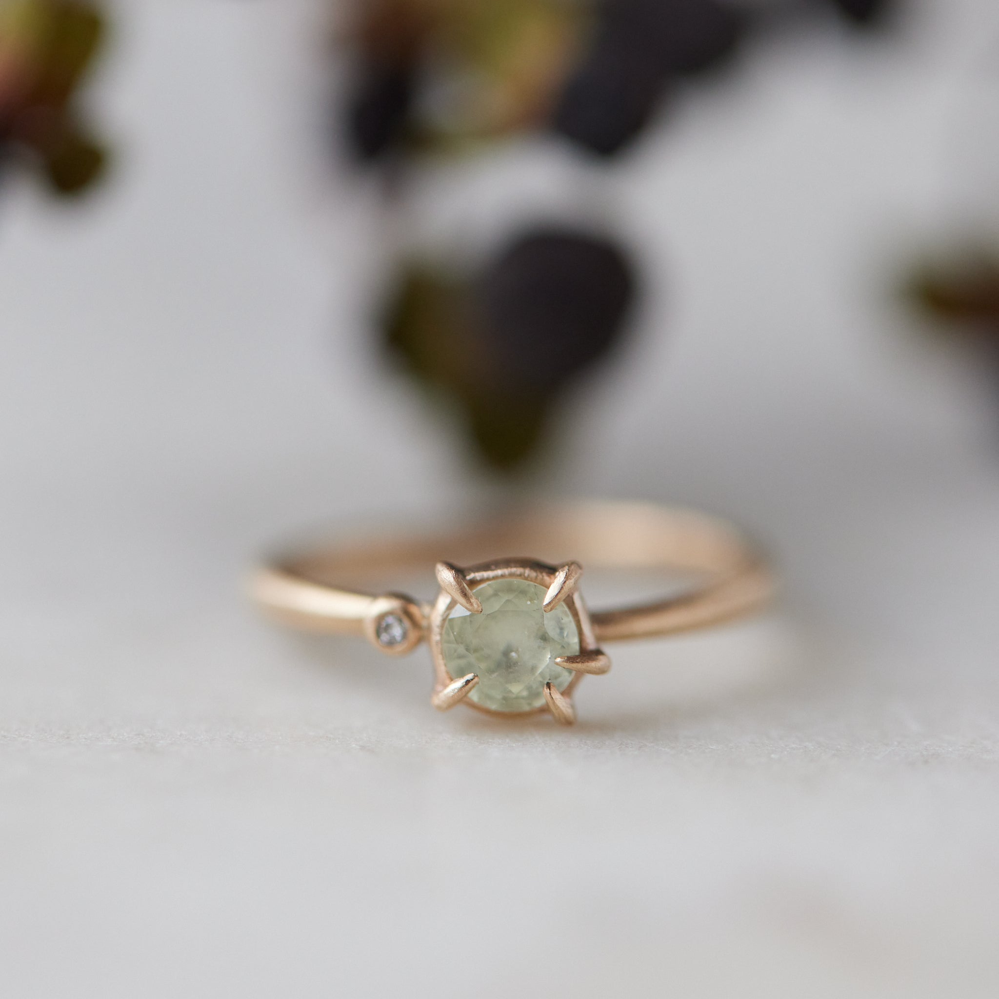 white sapphire set in a gold ring with a single white diamond on the side