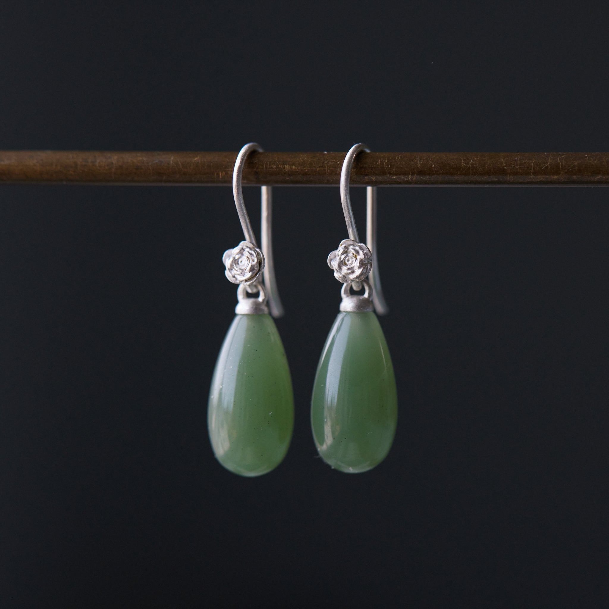 sage green nephrite jade teardrops hang beneath silver rose ear wires