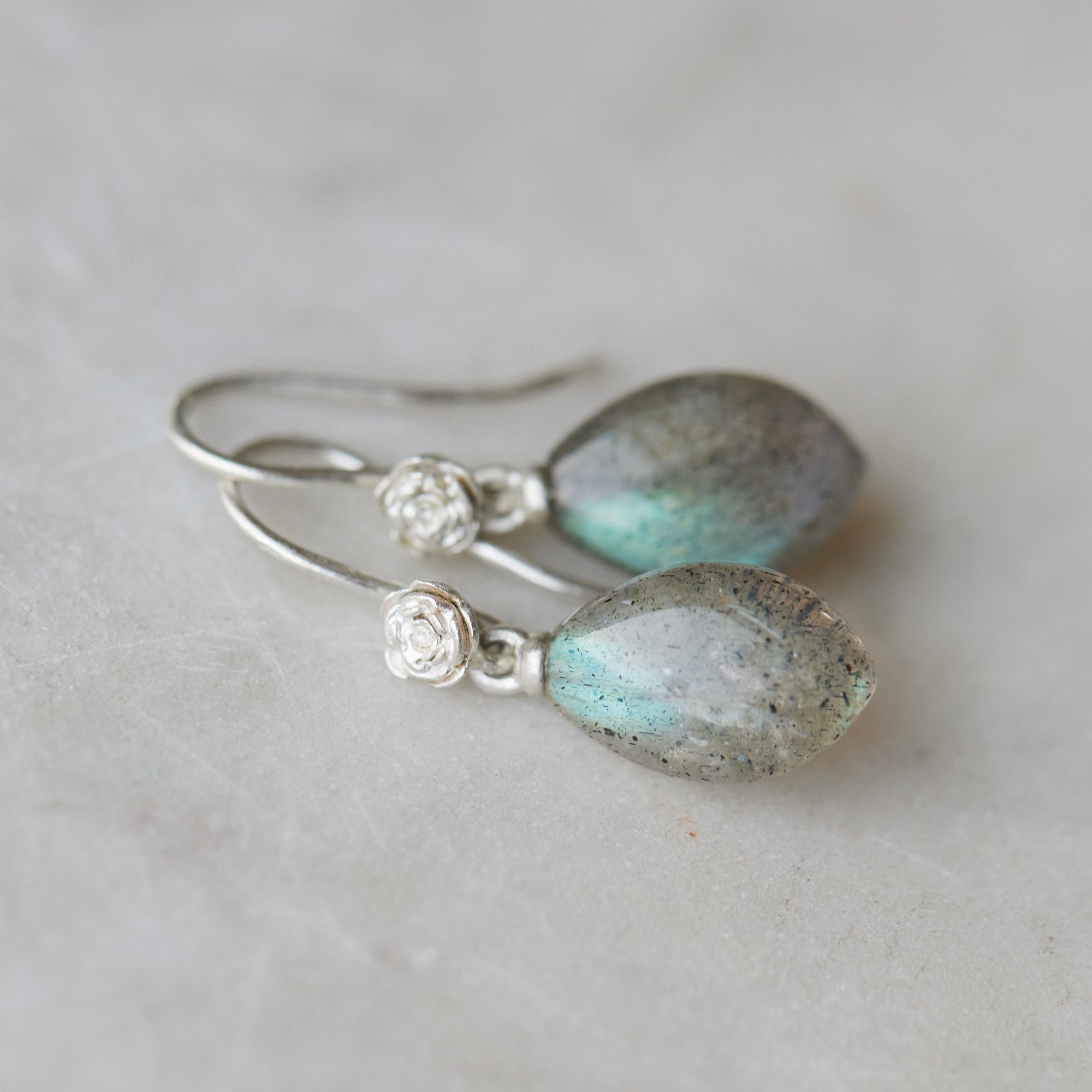 flashing with blue, grey labradorite cones hang beneath silver ear wires and roses. 
