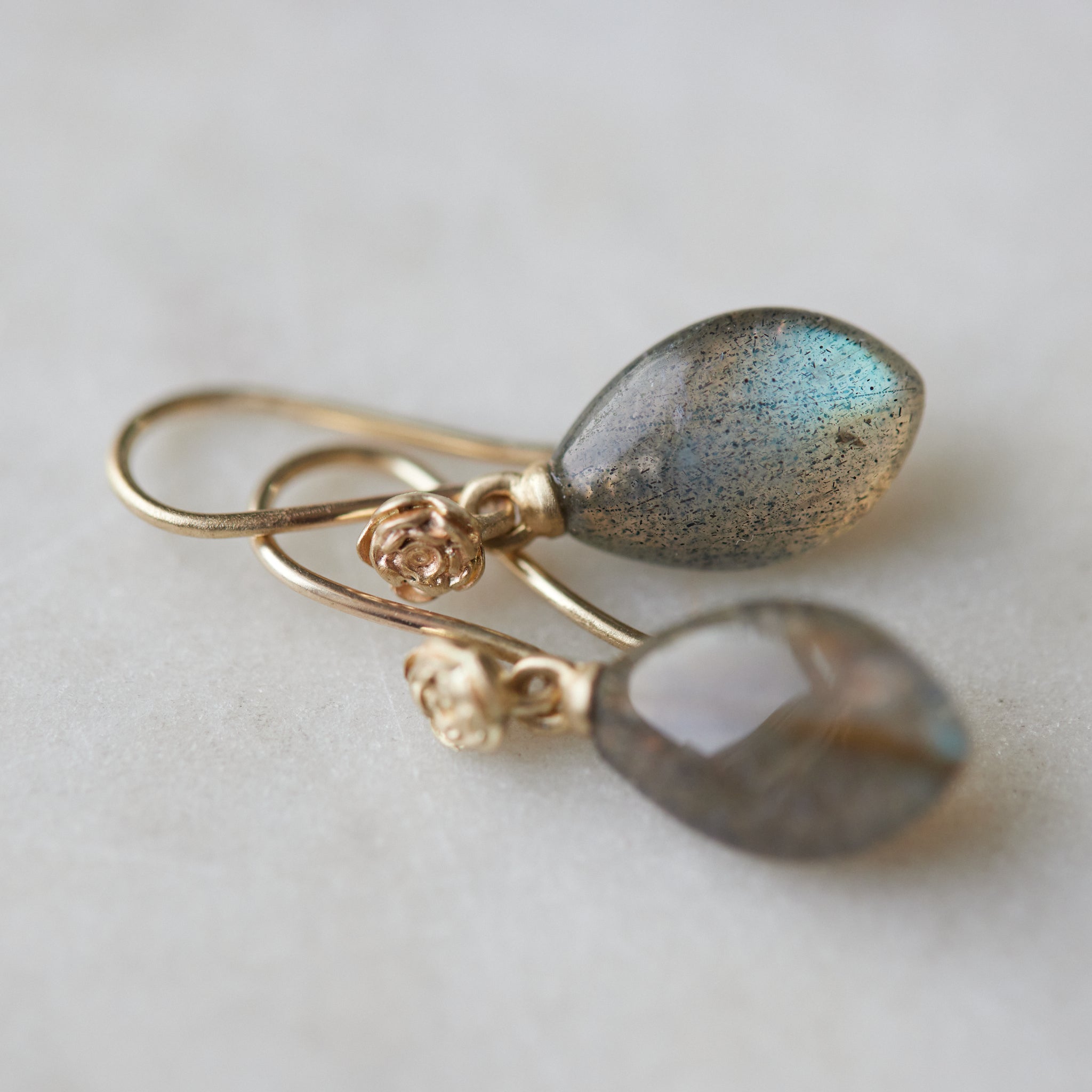 flashing with blue, grey labradorite cones hang beneath gold ear wires and roses. 