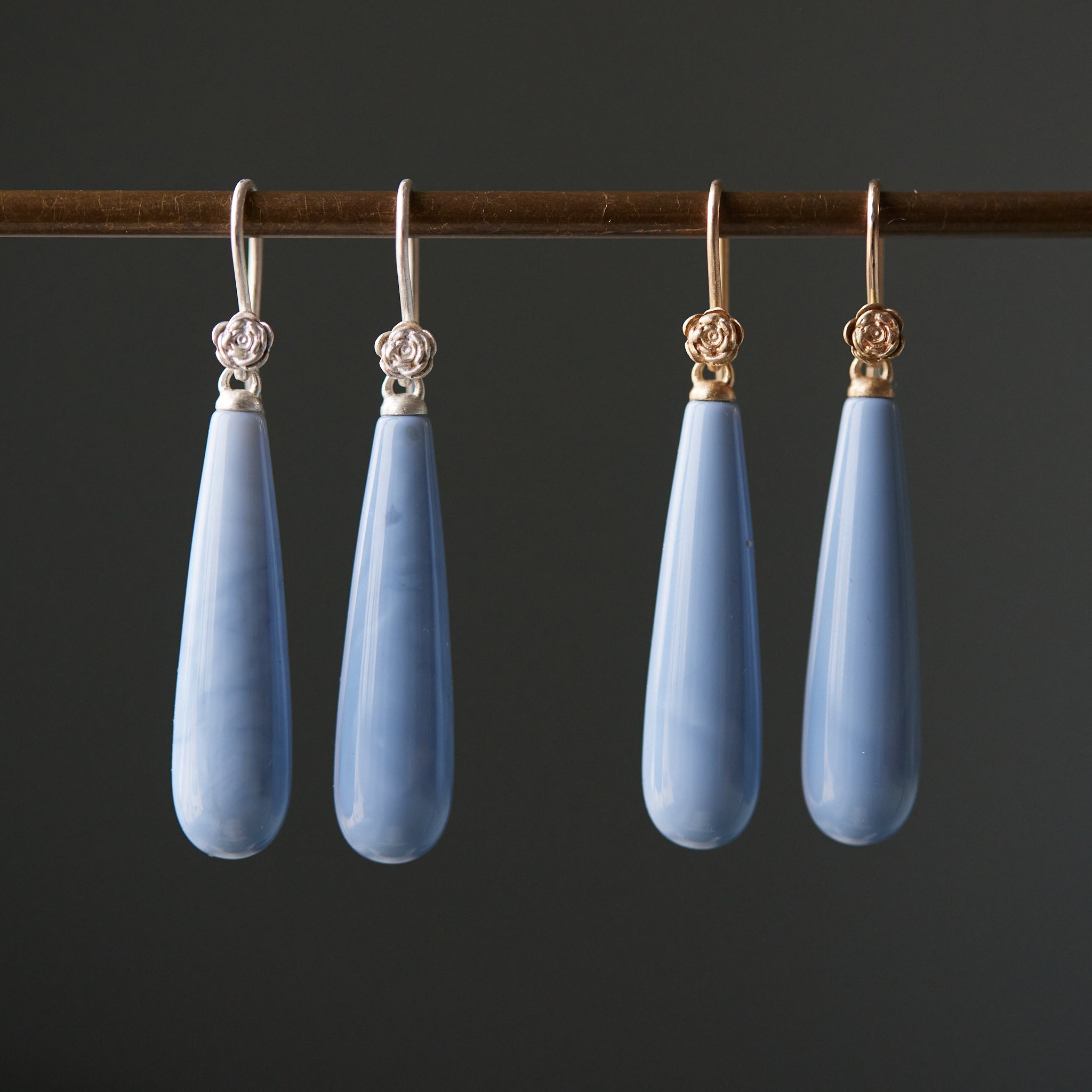 long teardrops of blue common opal hang beneath silver and gold ear wires and roses