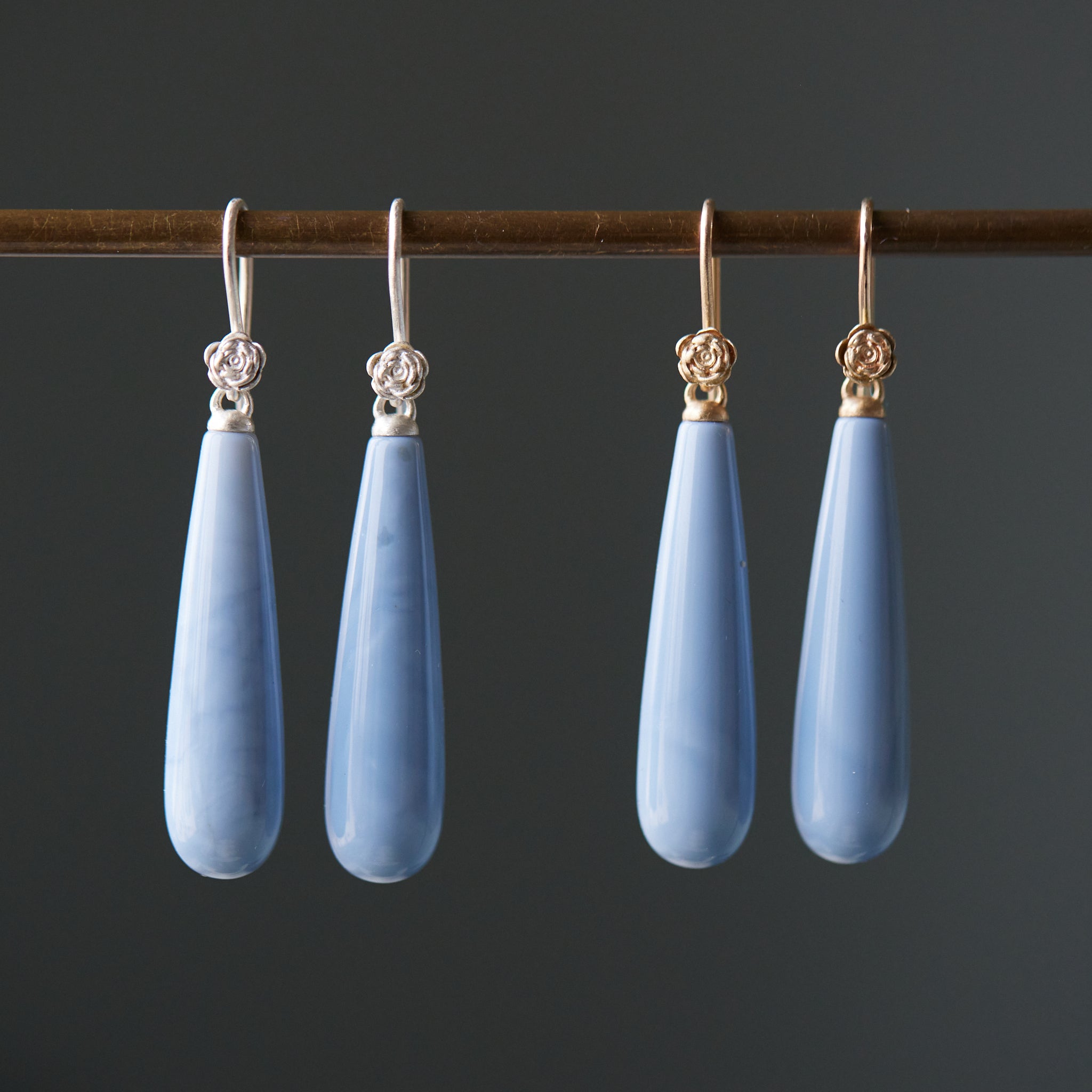 long teardrops of blue common opal hang beneath silver and gold ear wires and roses