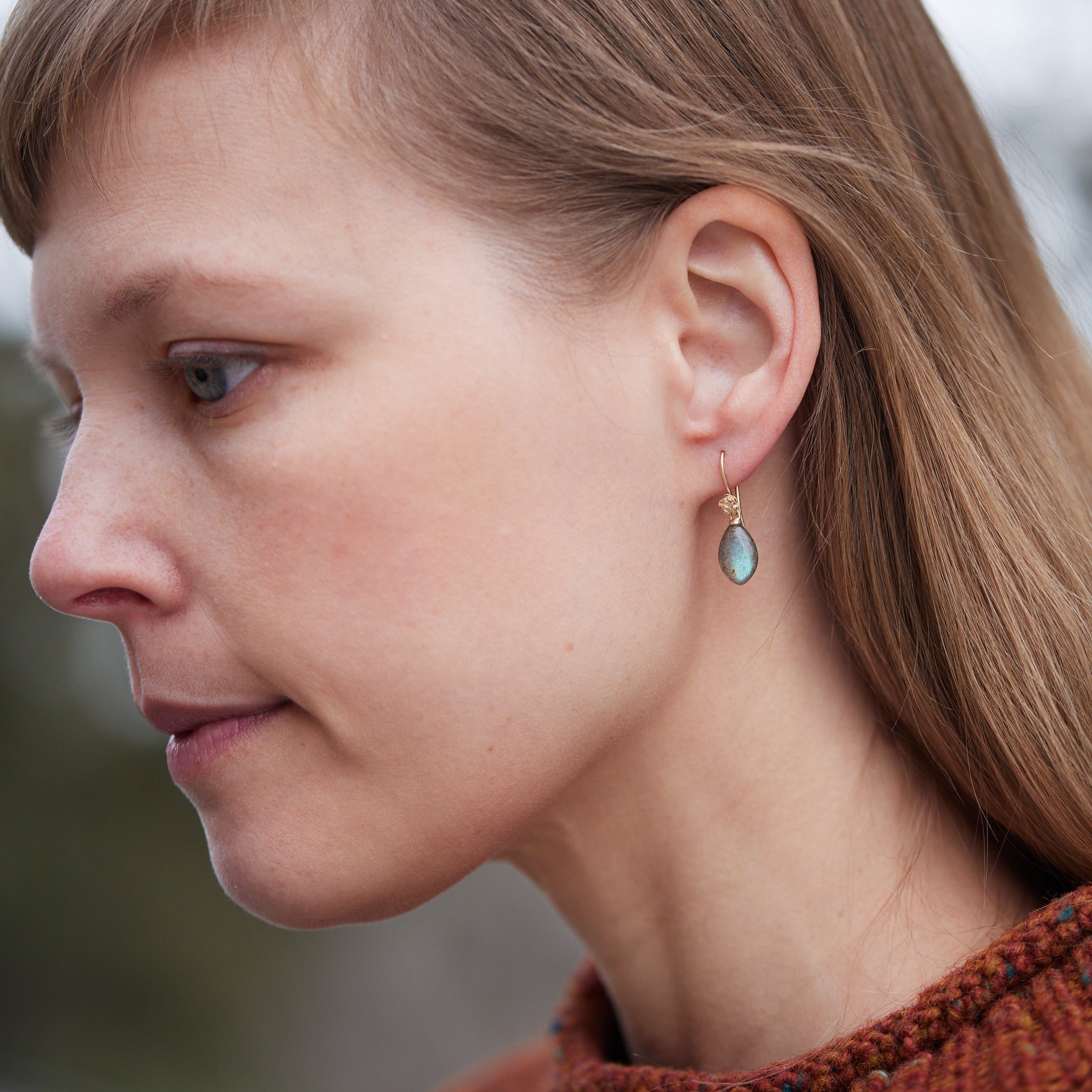 flashing with blue, grey labradorite cones hang beneath gold ear wires and roses. 