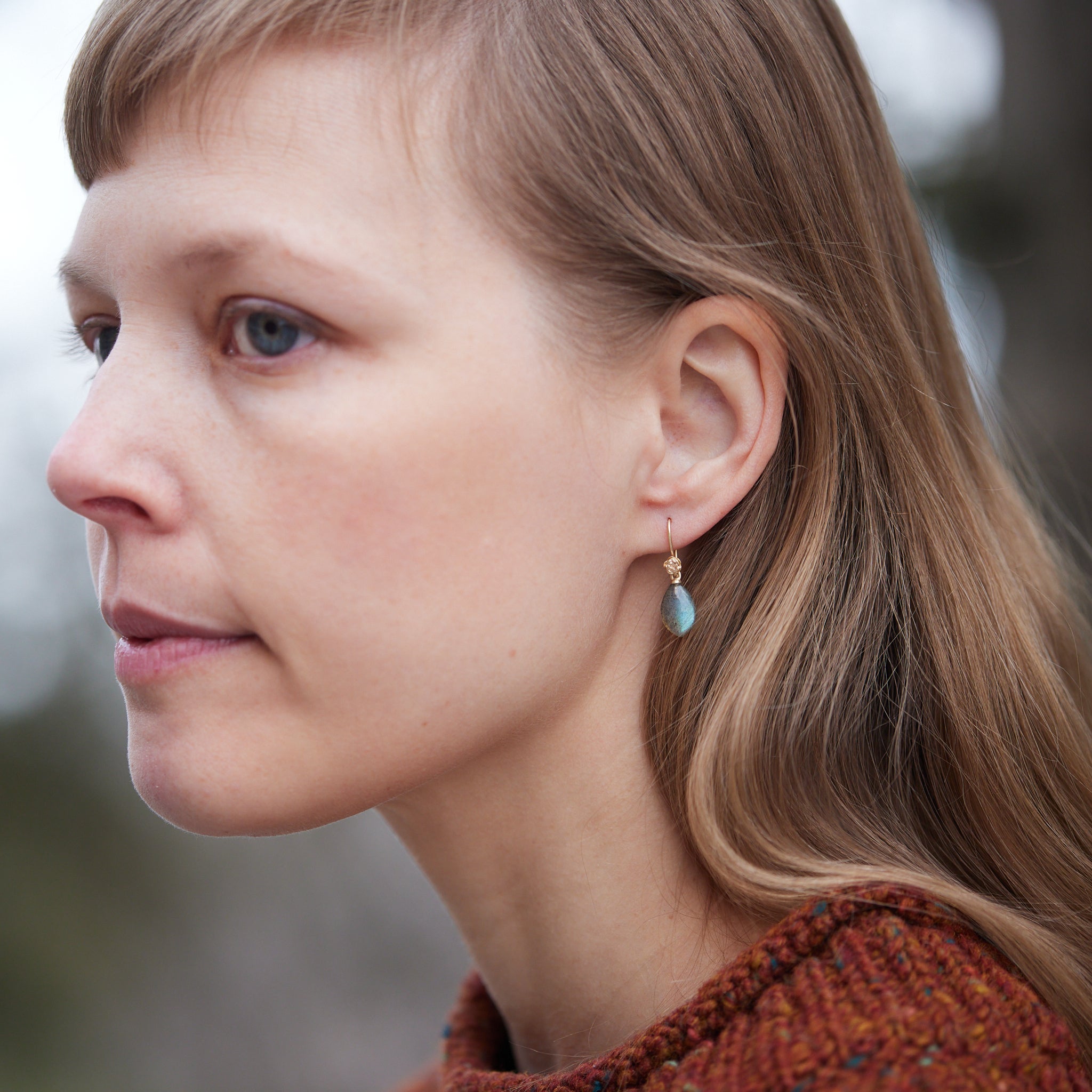 flashing with blue, grey labradorite cones hang beneath gold ear wires and roses. 