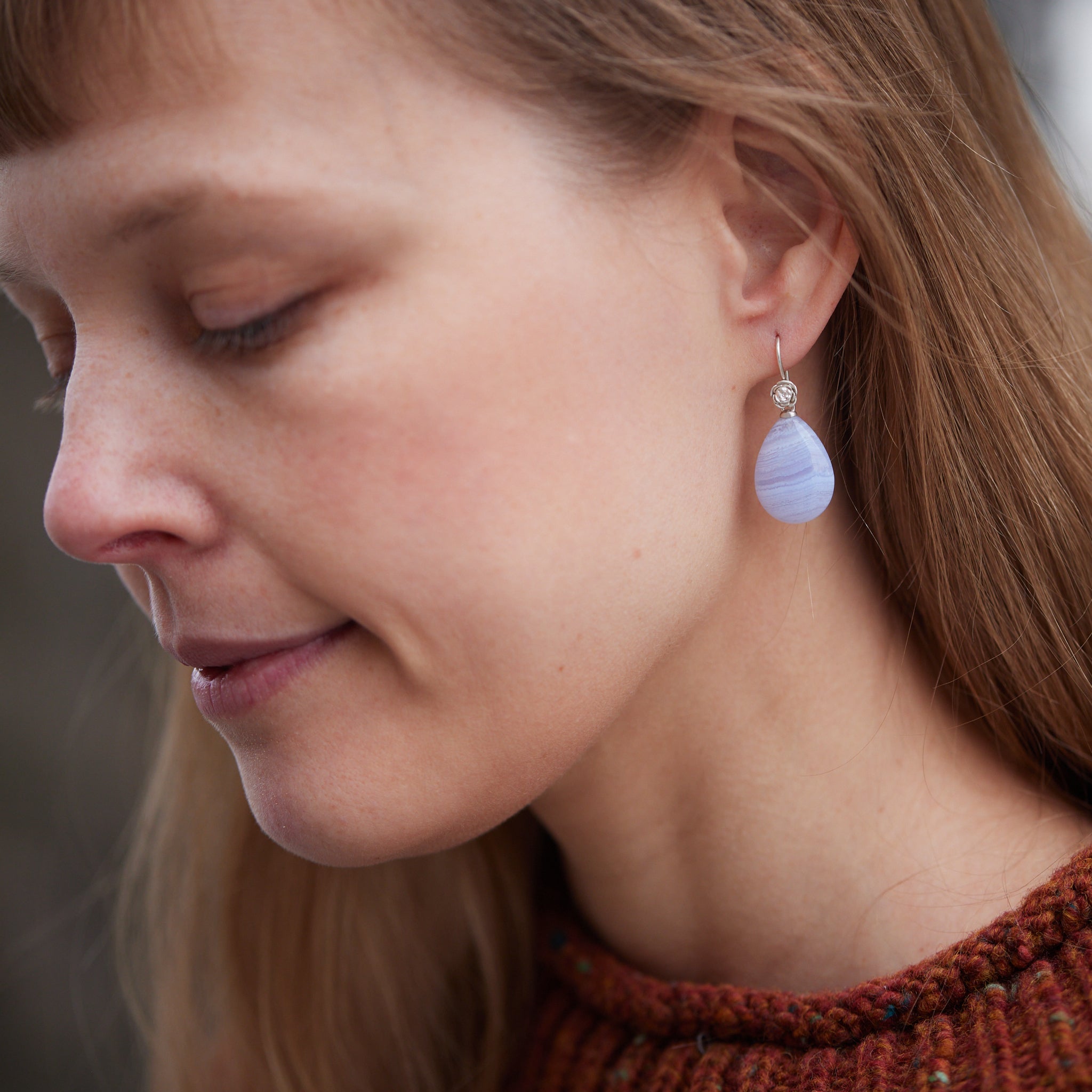swirly pale blue lace agate teardrops hang beneath silver ear wires featuring little silver roses on them