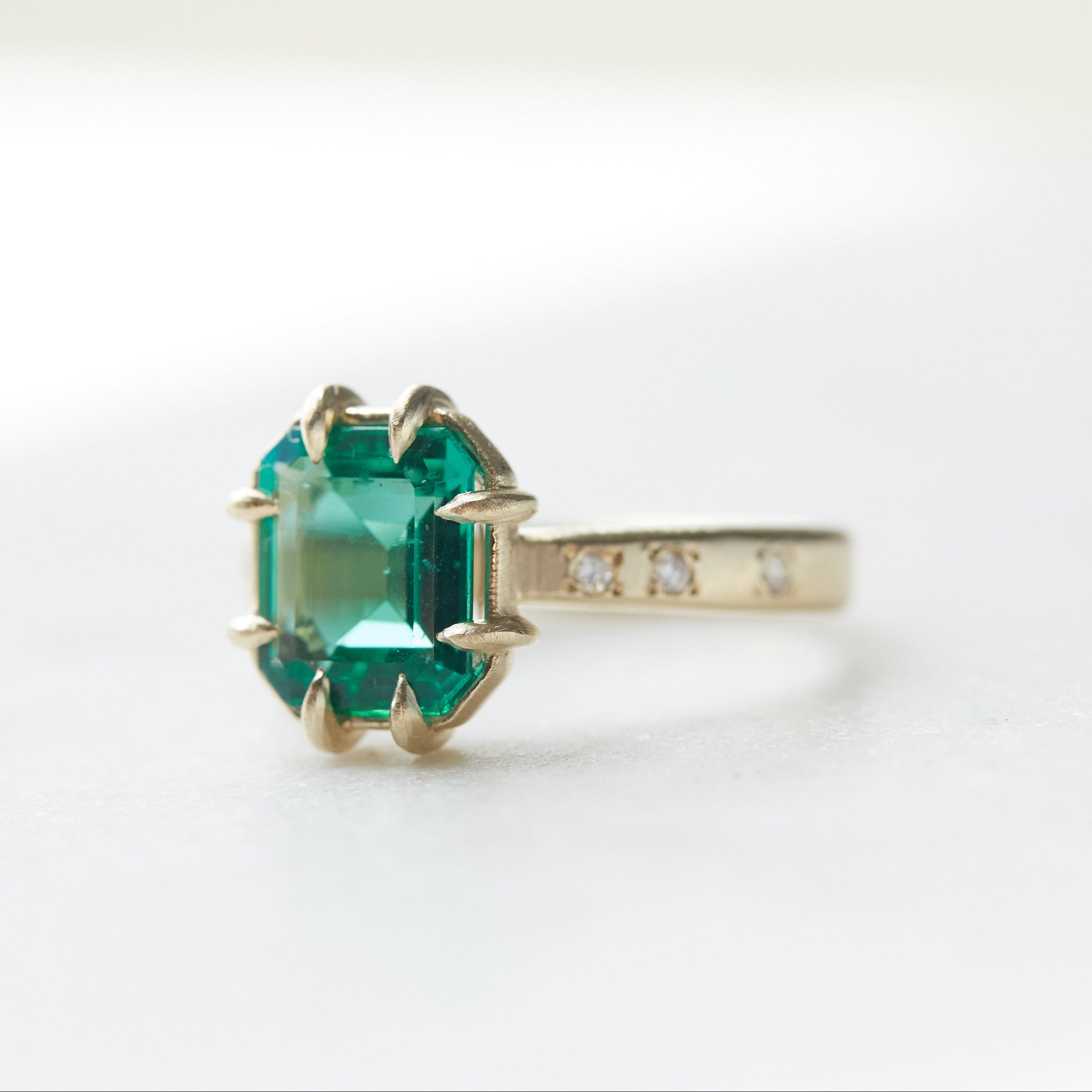 Gold ring with a green gemstone on a white background
