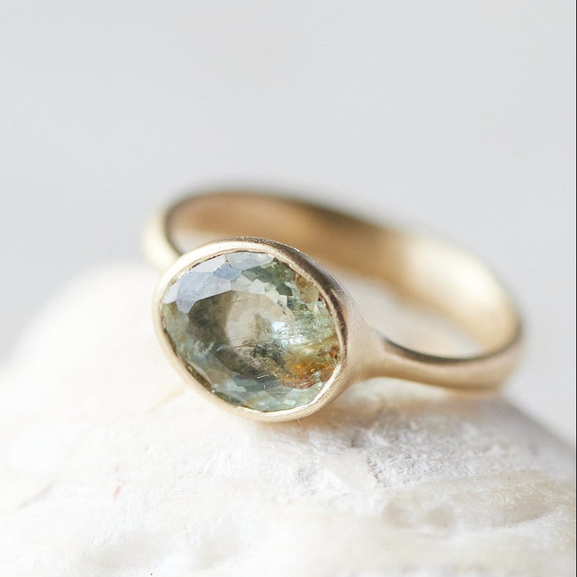 Gold ring with a green gemstone on a white stone