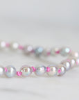 Pearl necklace with pink accents on a light gray background