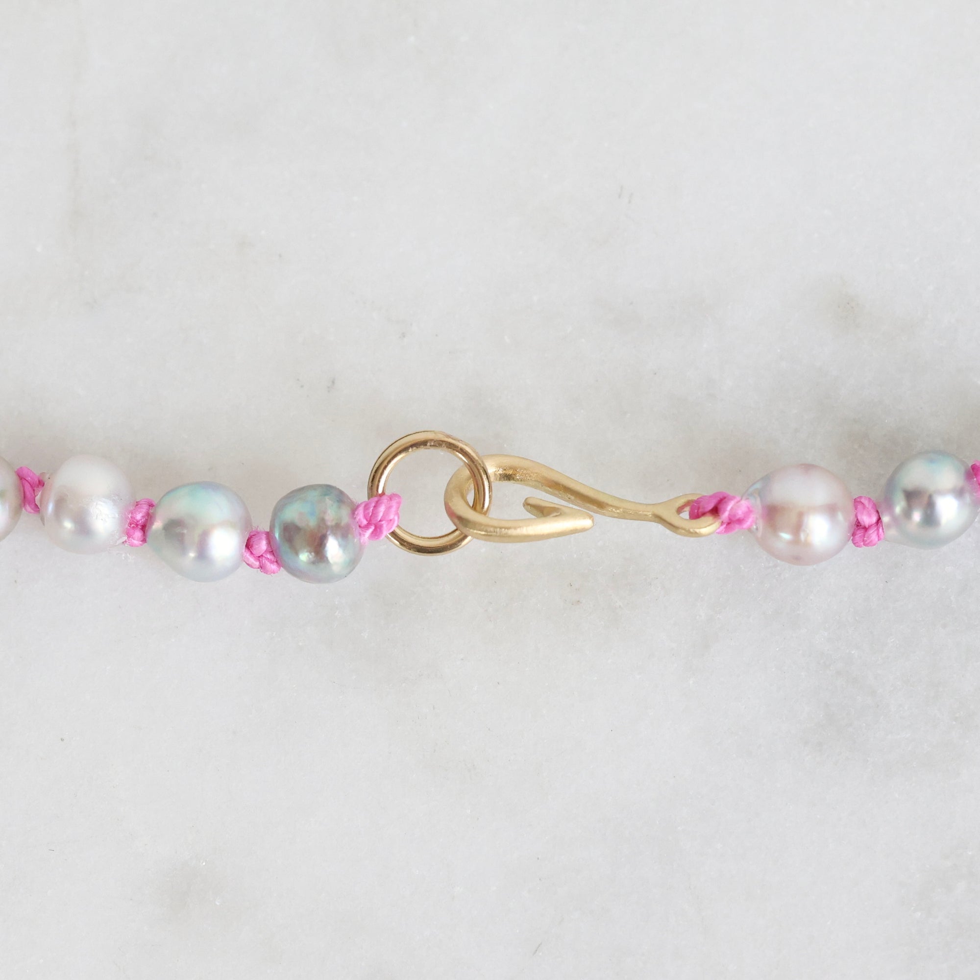 Pearl necklace with pink beads and gold clasp on a white background