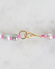 Pearl necklace with pink beads and gold clasp on a white background