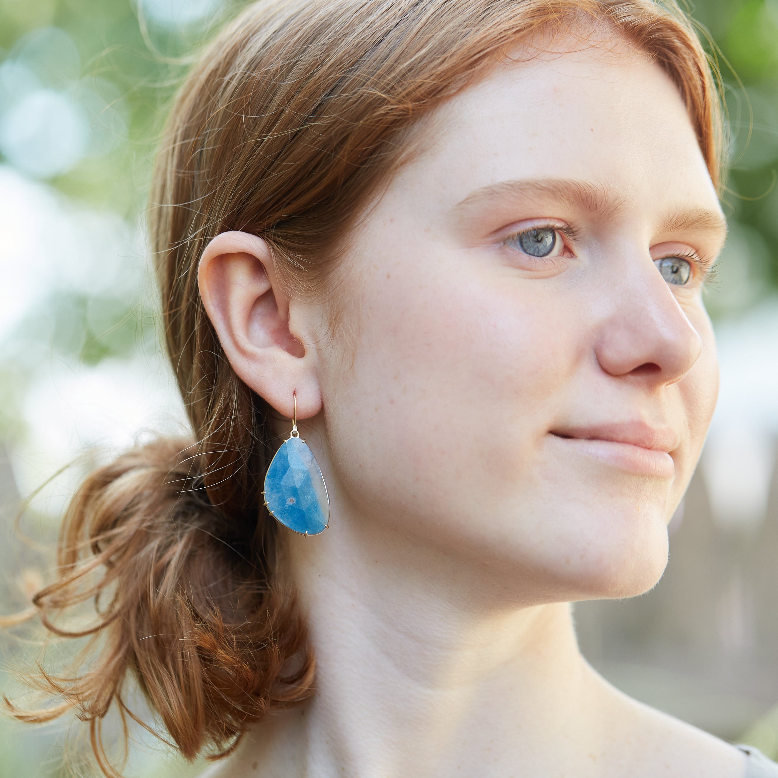 Blue pansy butterfly paraiba in quartz earrings with prongs on person by hannah blount jewelry