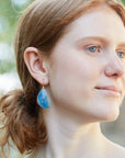 Blue pansy butterfly paraiba in quartz earrings with prongs on person by hannah blount jewelry