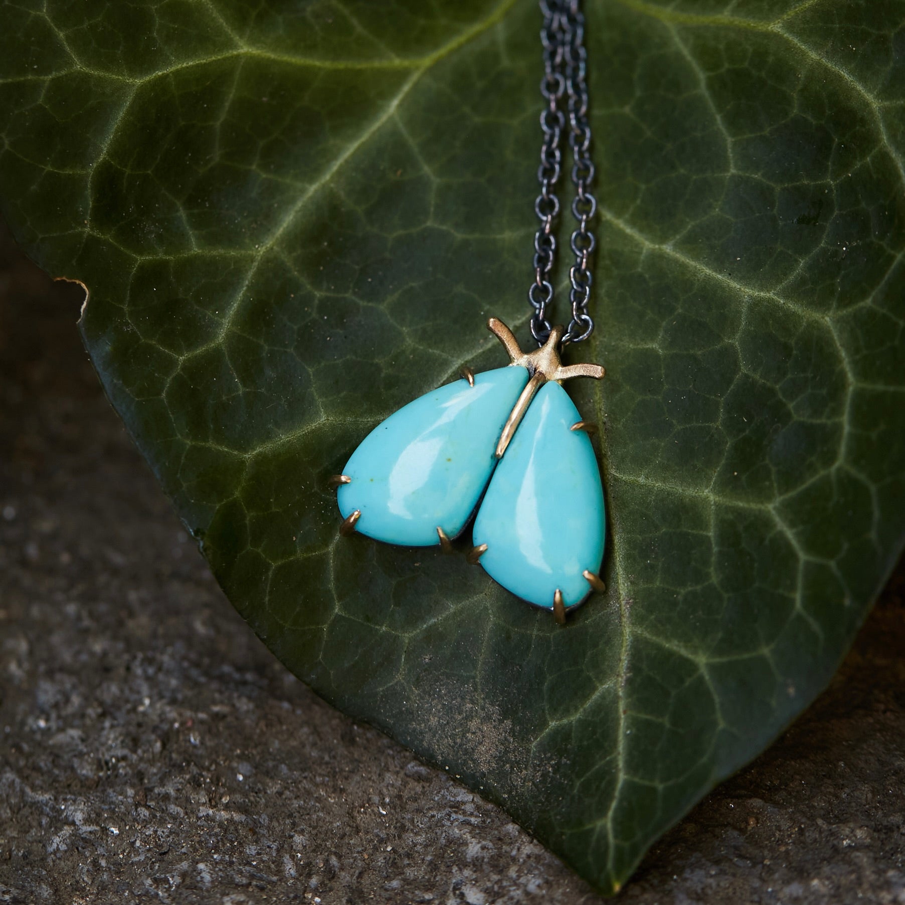 kingman turquoise longtail moth necklace with prongs on leaf by hannah blount jewelry